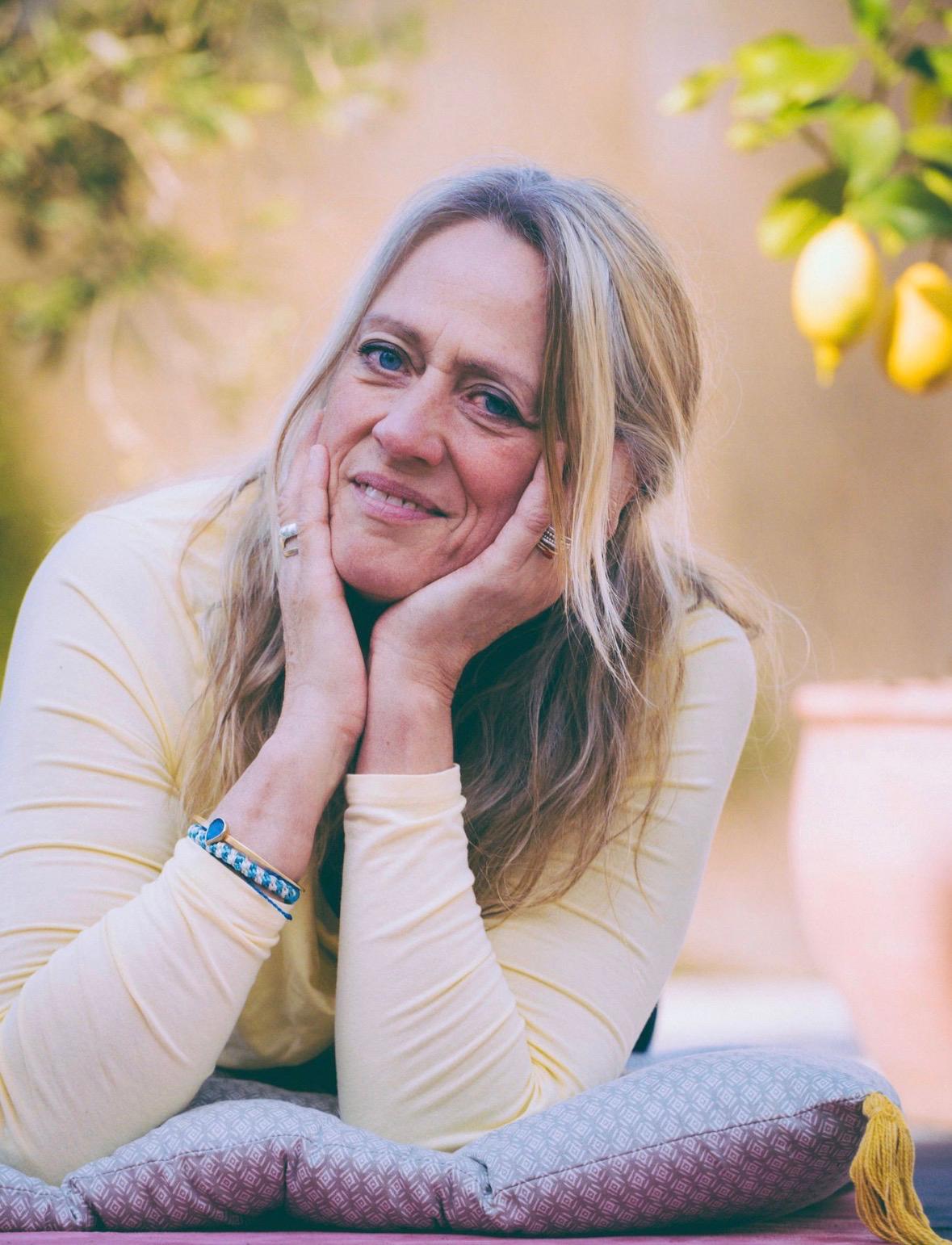 Annette von Casa Limoni – entspannt lächelnd auf einem Yogakissen unter Zitronenbäumen