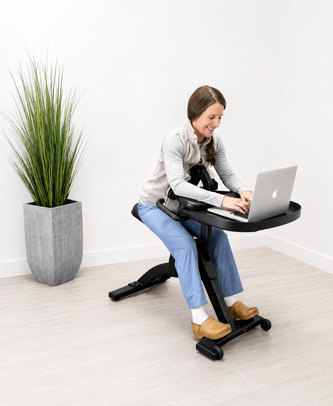 Woman using Boddie Balance Workstation positioning system — full body view showing chair legs and feet