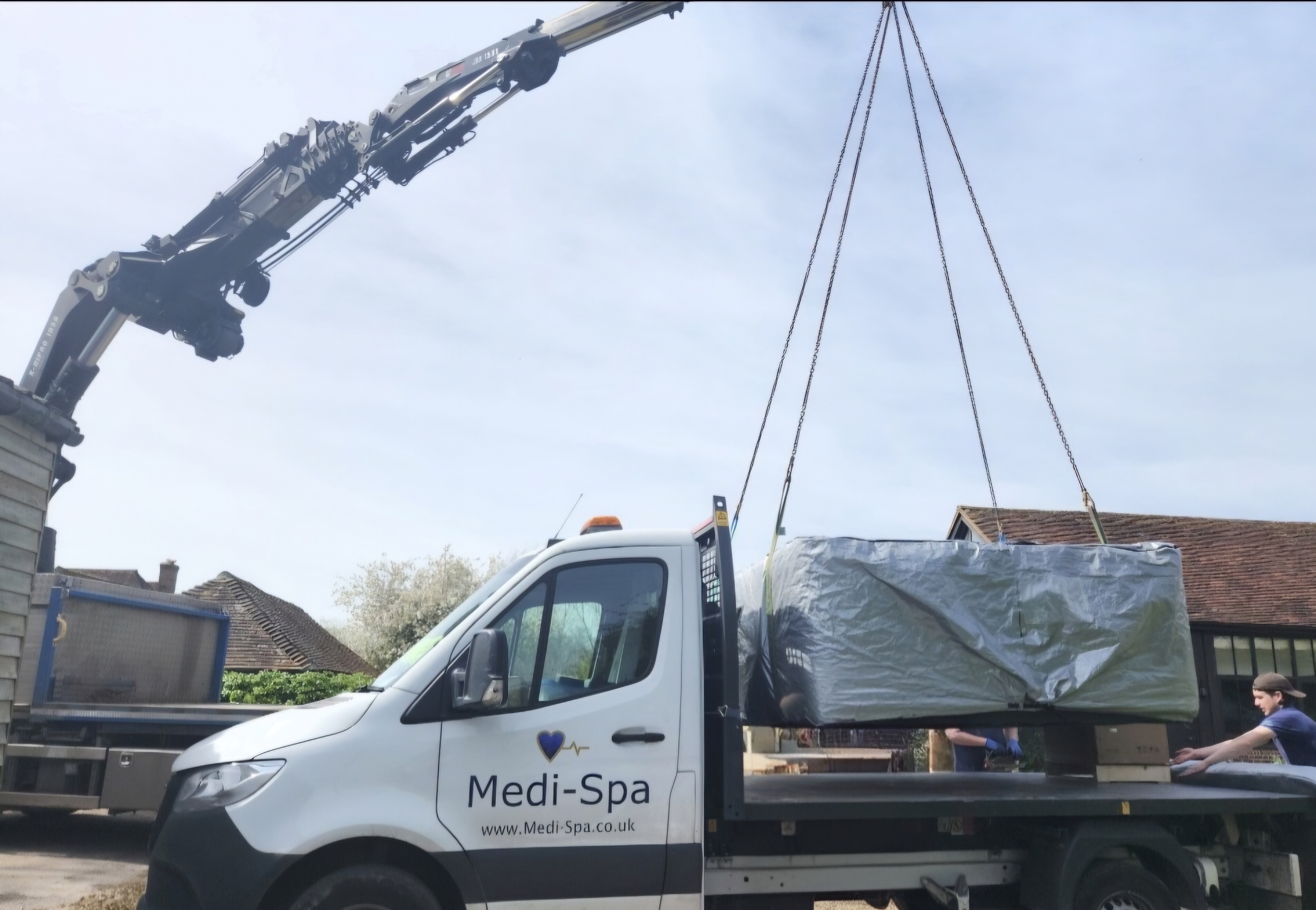 Medi-Spa branded truck with crane lifting a hot tub