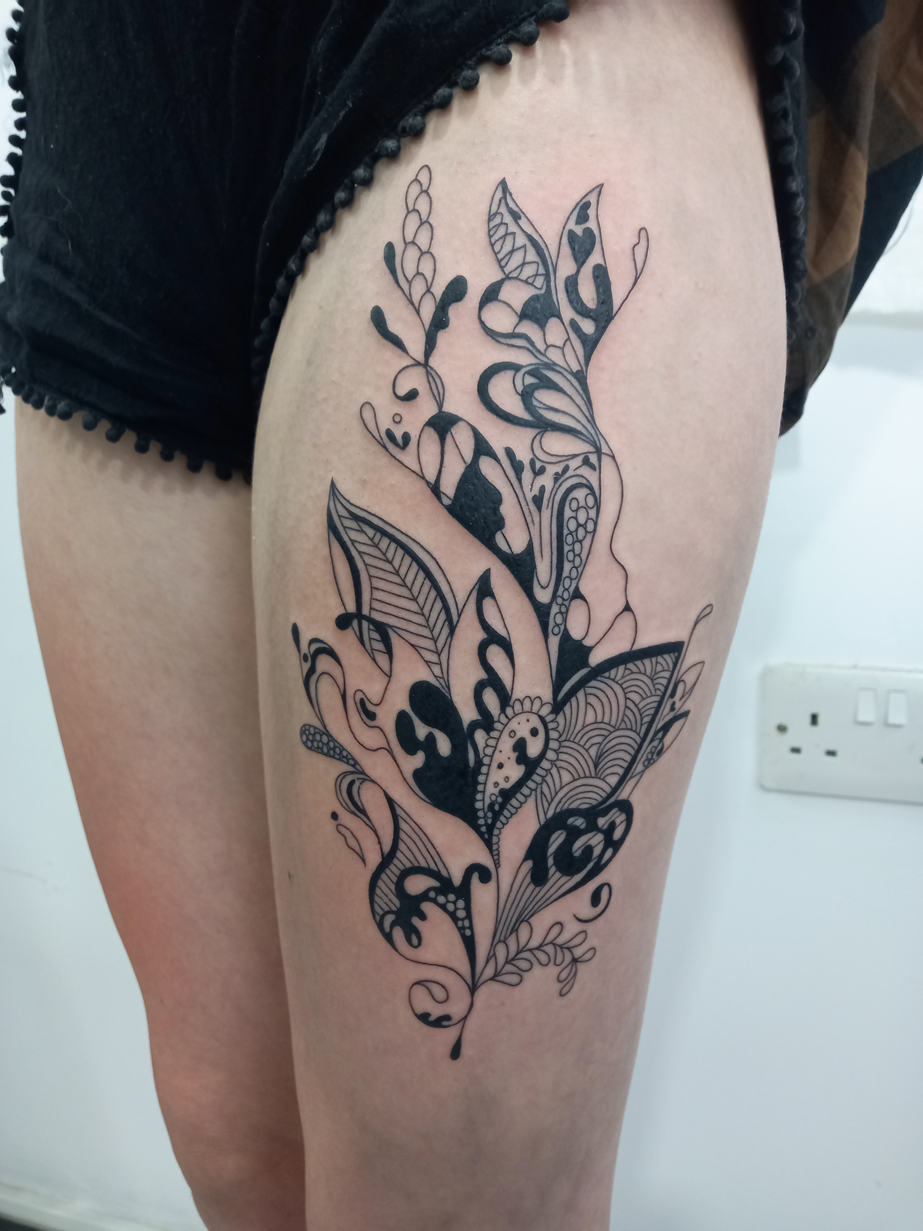 Bold blackwork abstract floral botanical thigh tattoo by Tori Talio