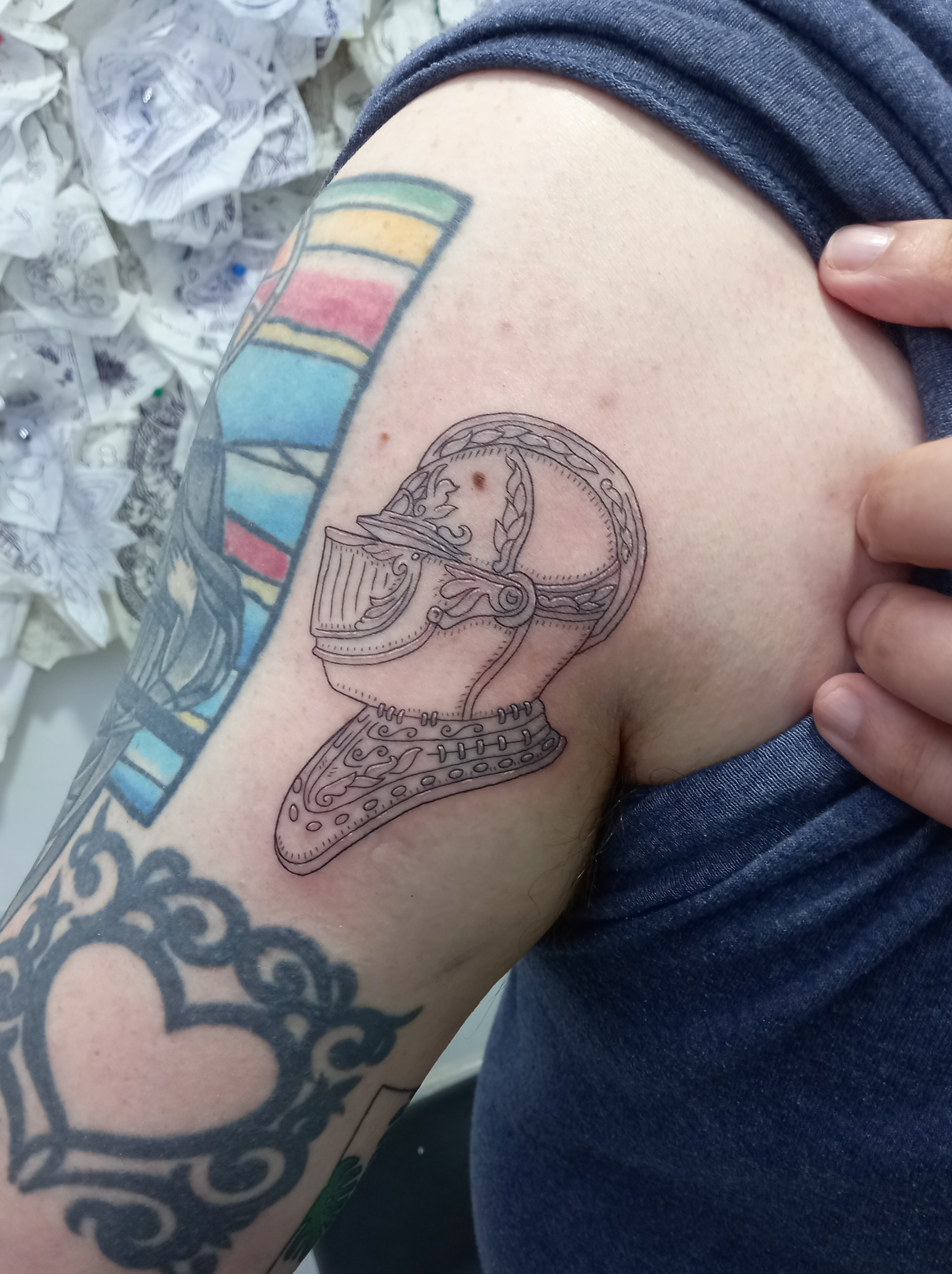 Medieval knights helmet fine line shoulder tattoo by Tori Talio