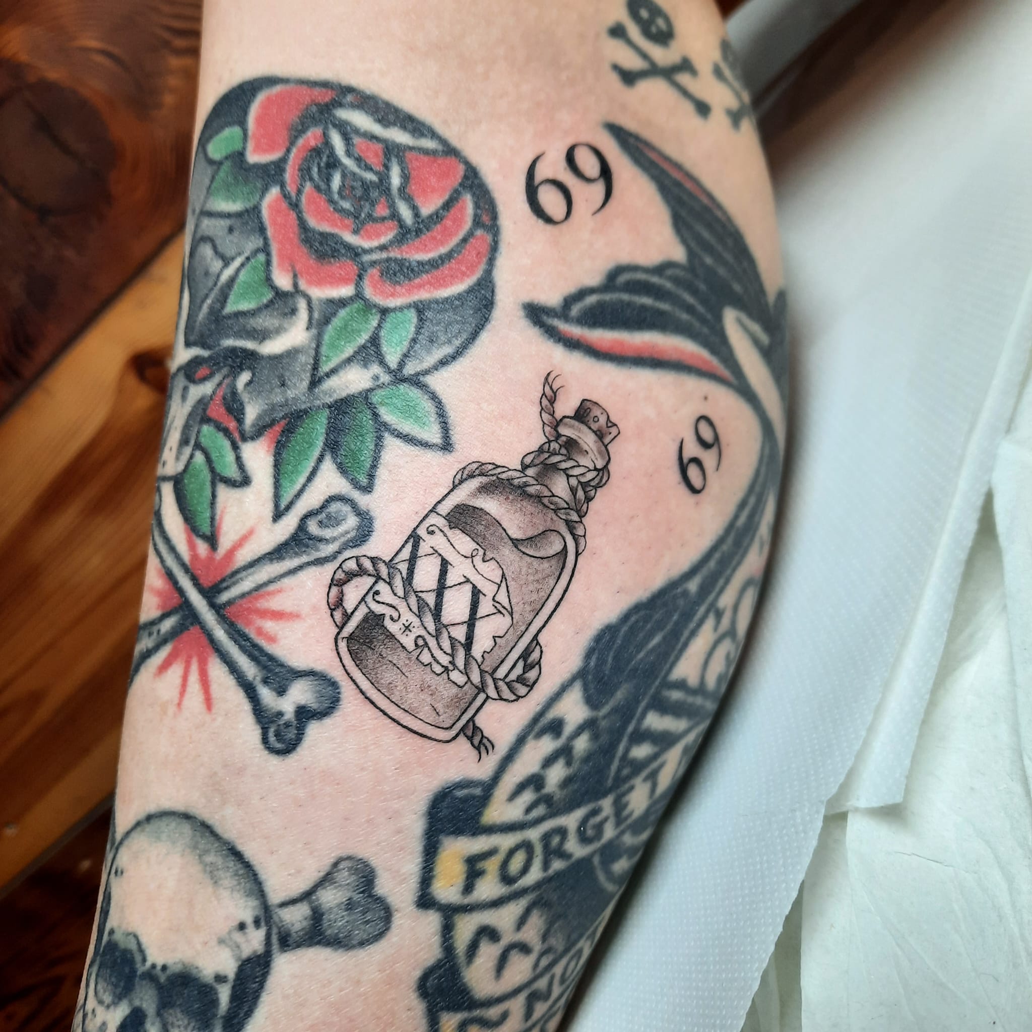 Traditional flash rose bottle swallow skulls tattoo by Luca Falzon
