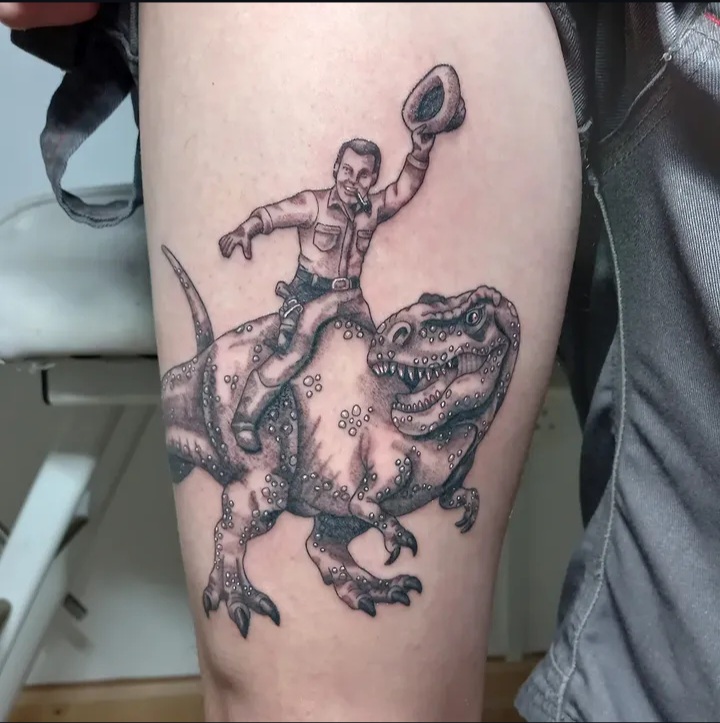Cowboy riding T-Rex thigh tattoo by Tori Talio