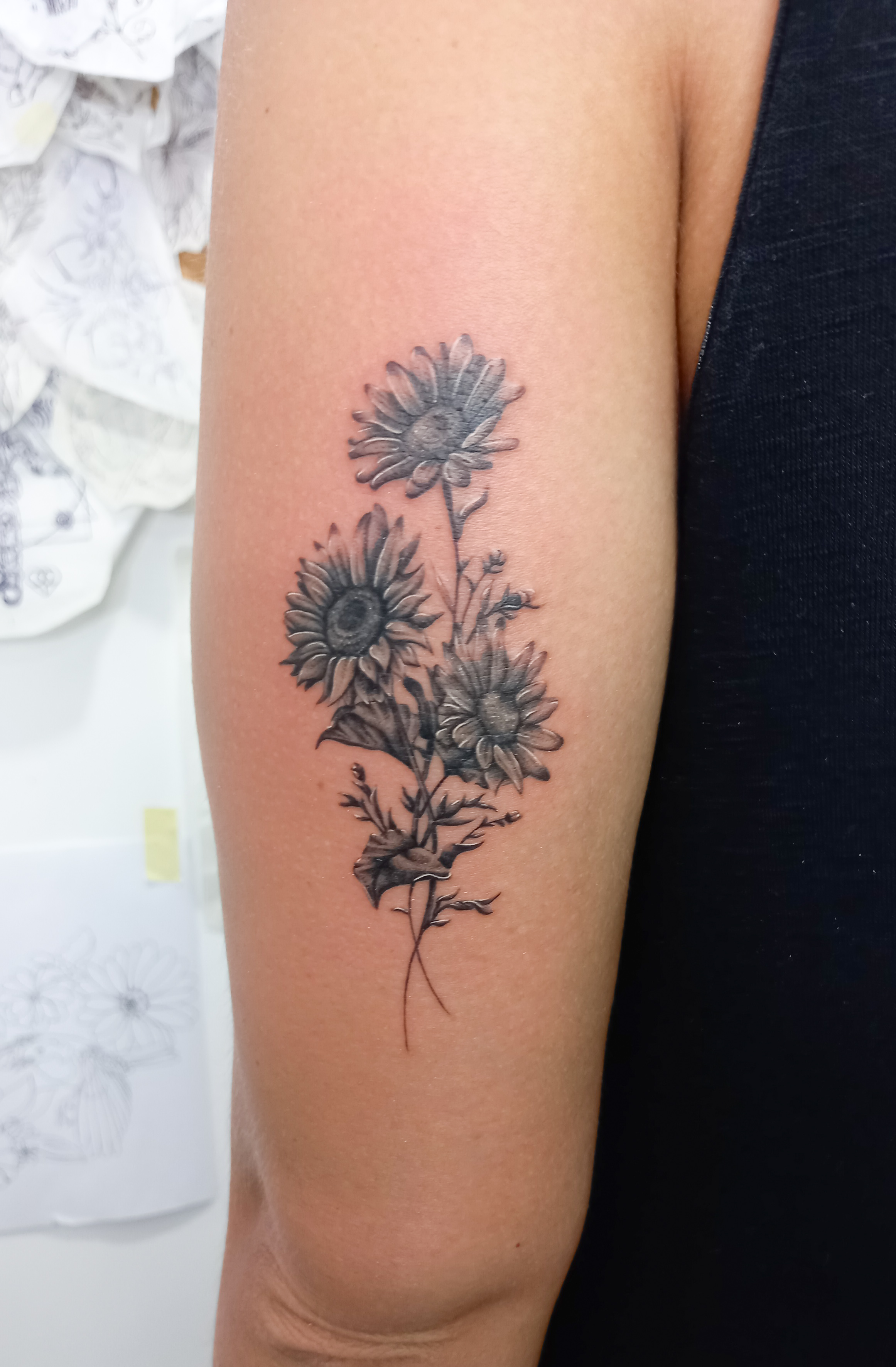 Daisy bouquet black and grey upper arm tattoo by Tori Talio