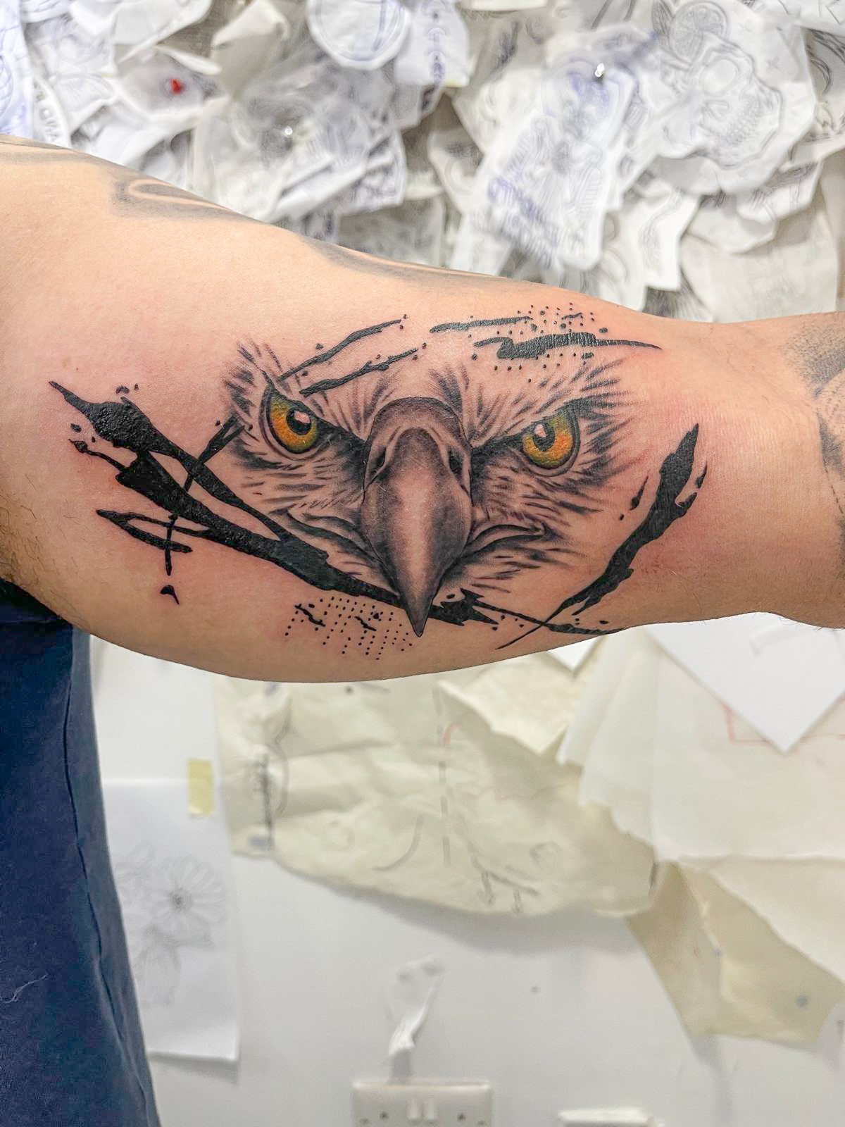 Eagle face with ink splatter bicep tattoo by Tori Talio