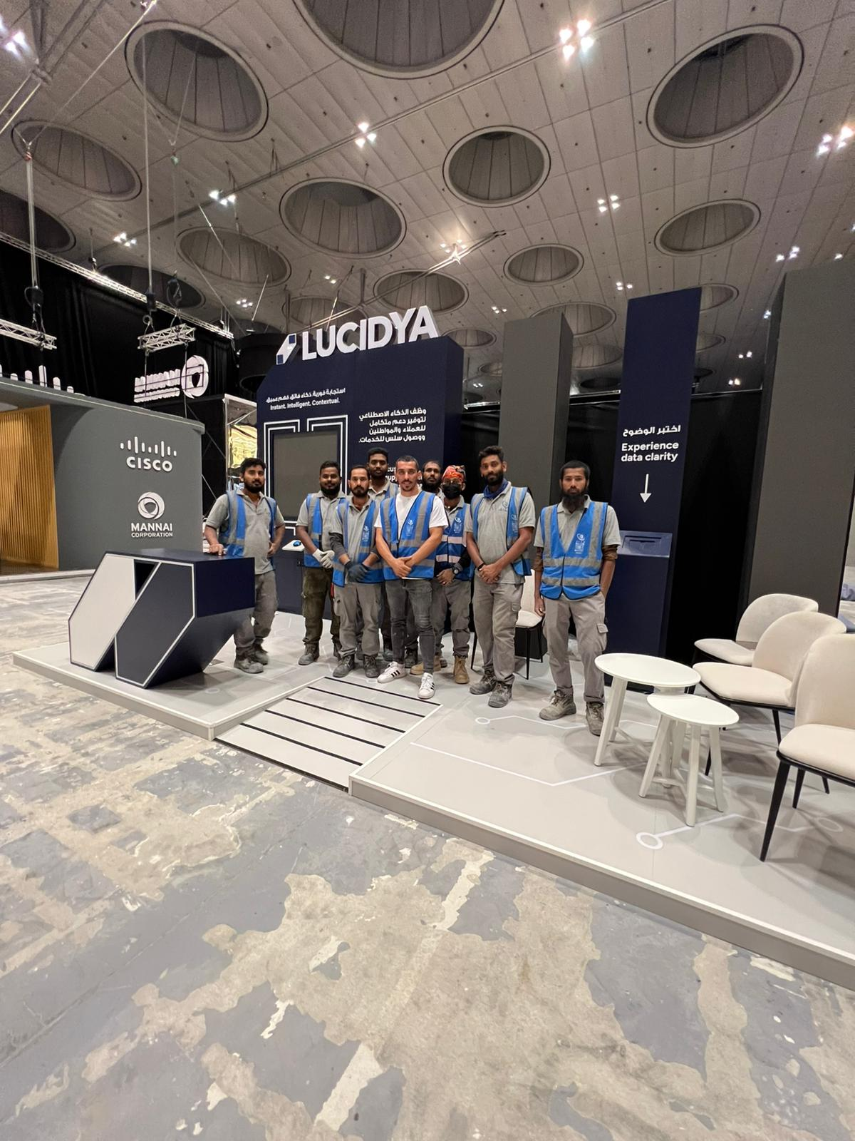 ELCO team in branded blue safety vests at a completed exhibition booth build for Lucidya at a conference venue