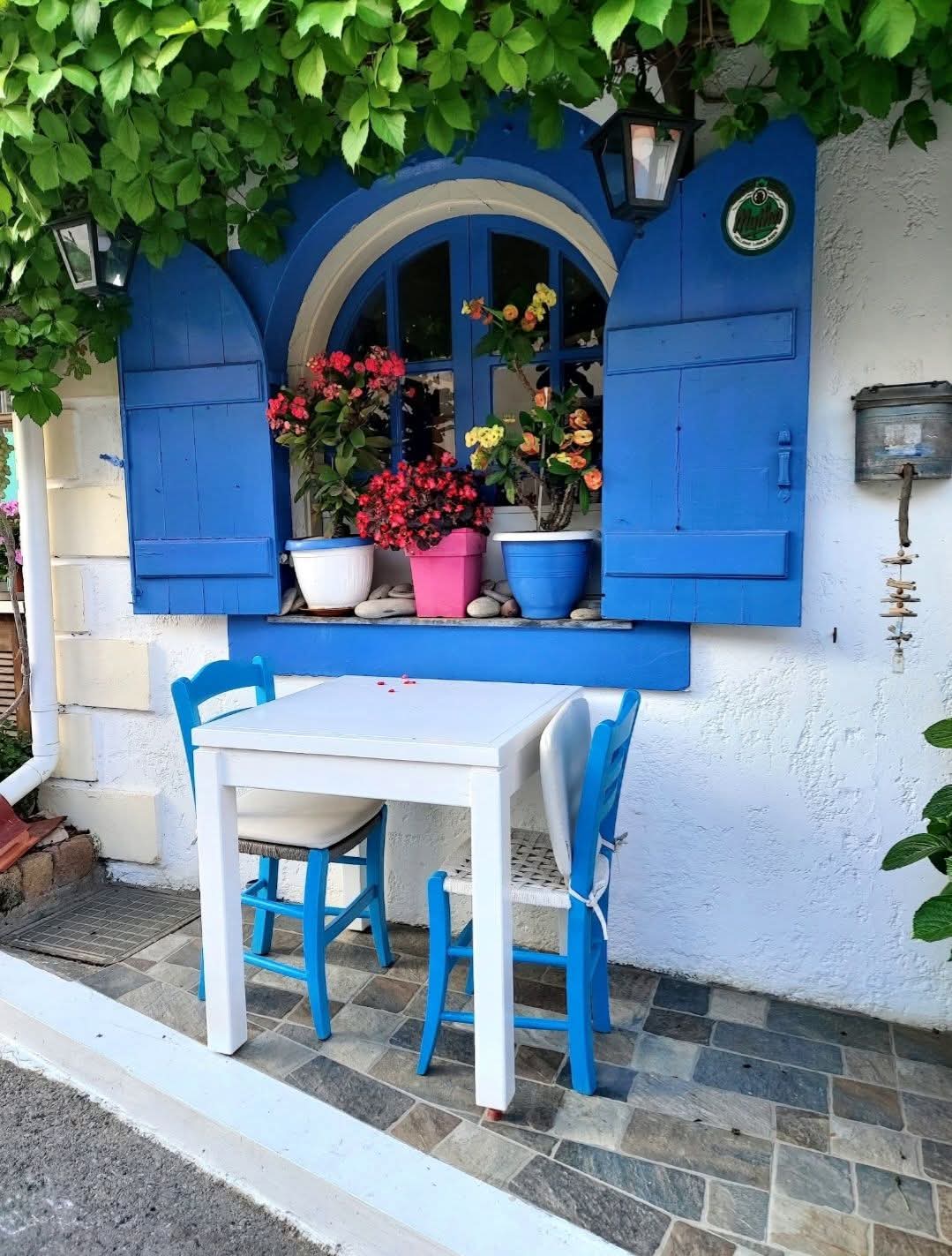 Charming blue shuttered window with flowers in Crete
