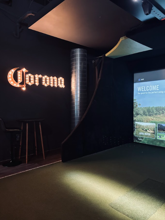 Simulateur de golf avec ambiance bar lounge et enseigne Corona - soirée golf intérieur au Golf Lounge Sherbrooke
