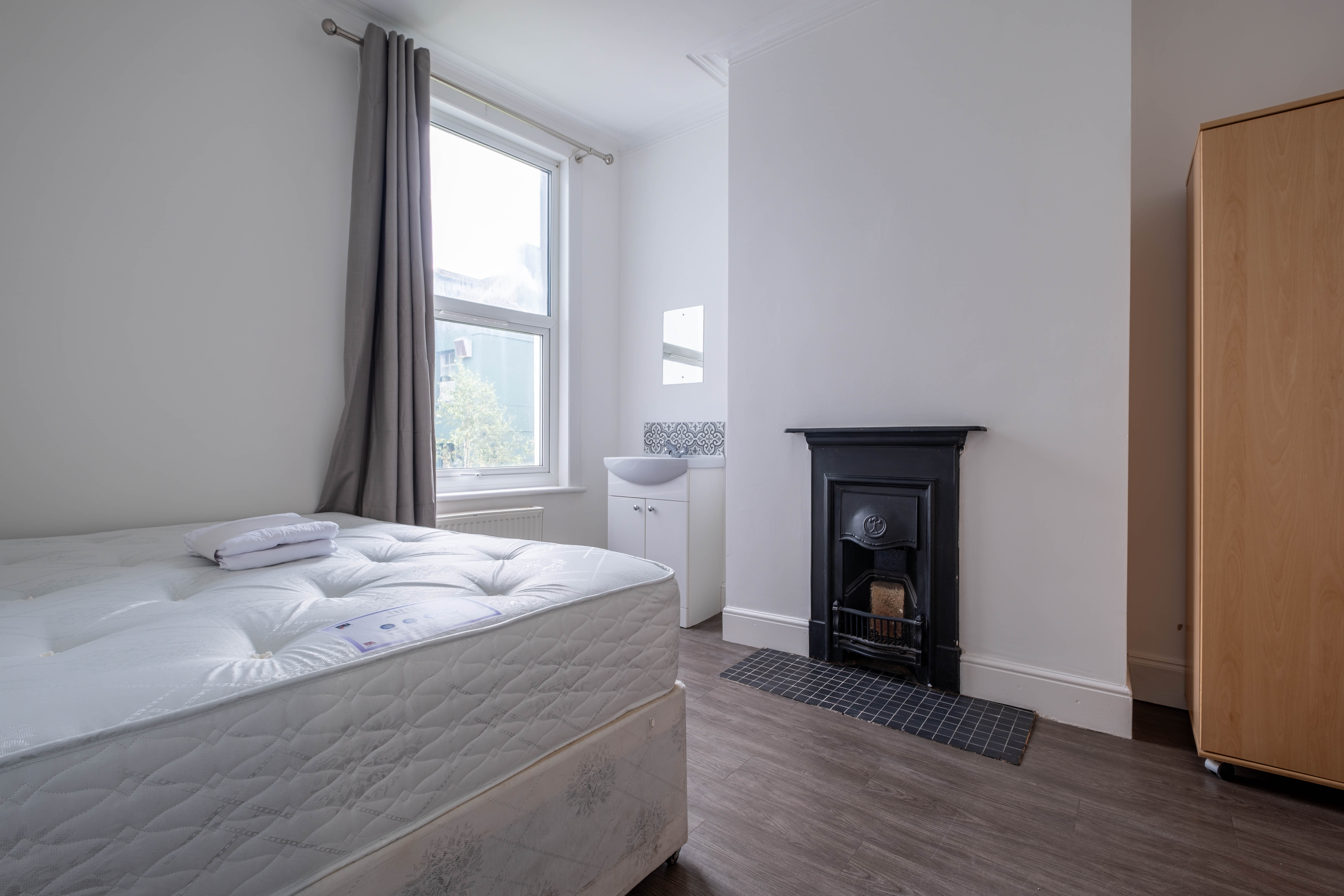 Bright bedroom with original cast-iron fireplace and period features — Brighton rental property photography