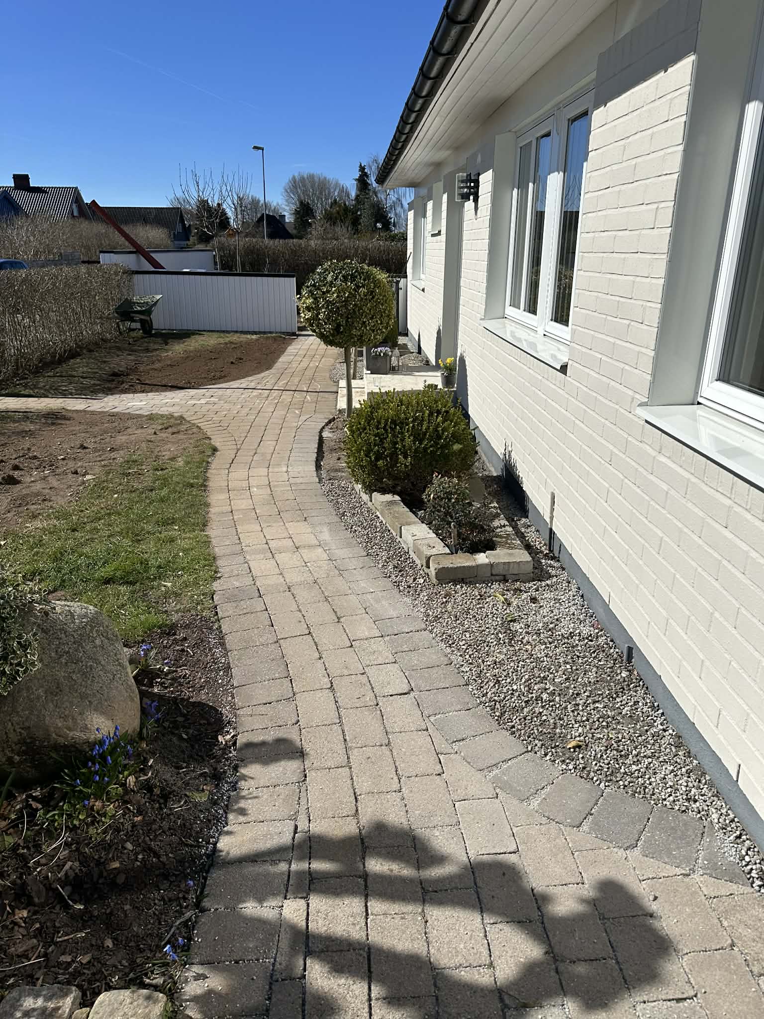 Färdiglagd gångväg i marksten med planteringar och grus