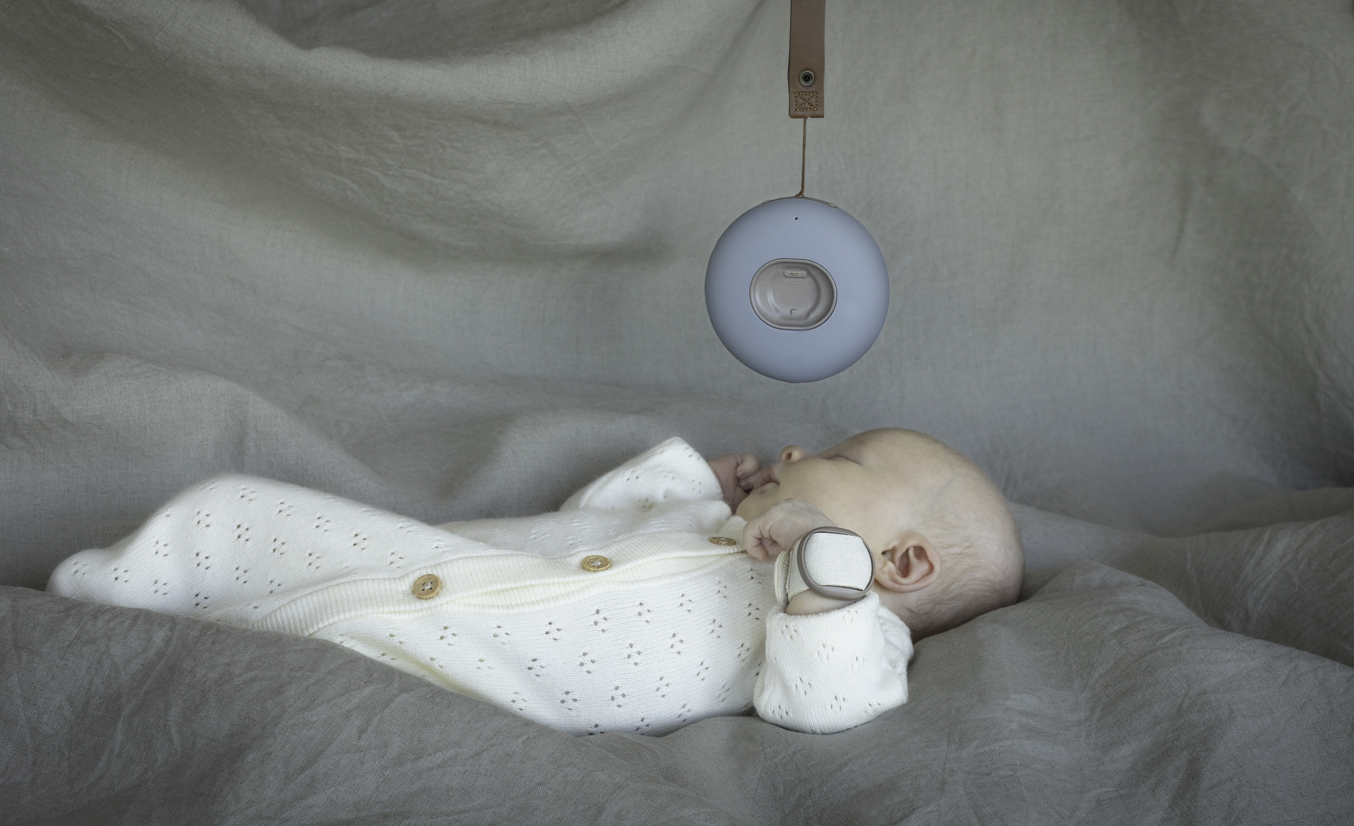 Sleeping baby with BabySensor wearable bracelet and base station