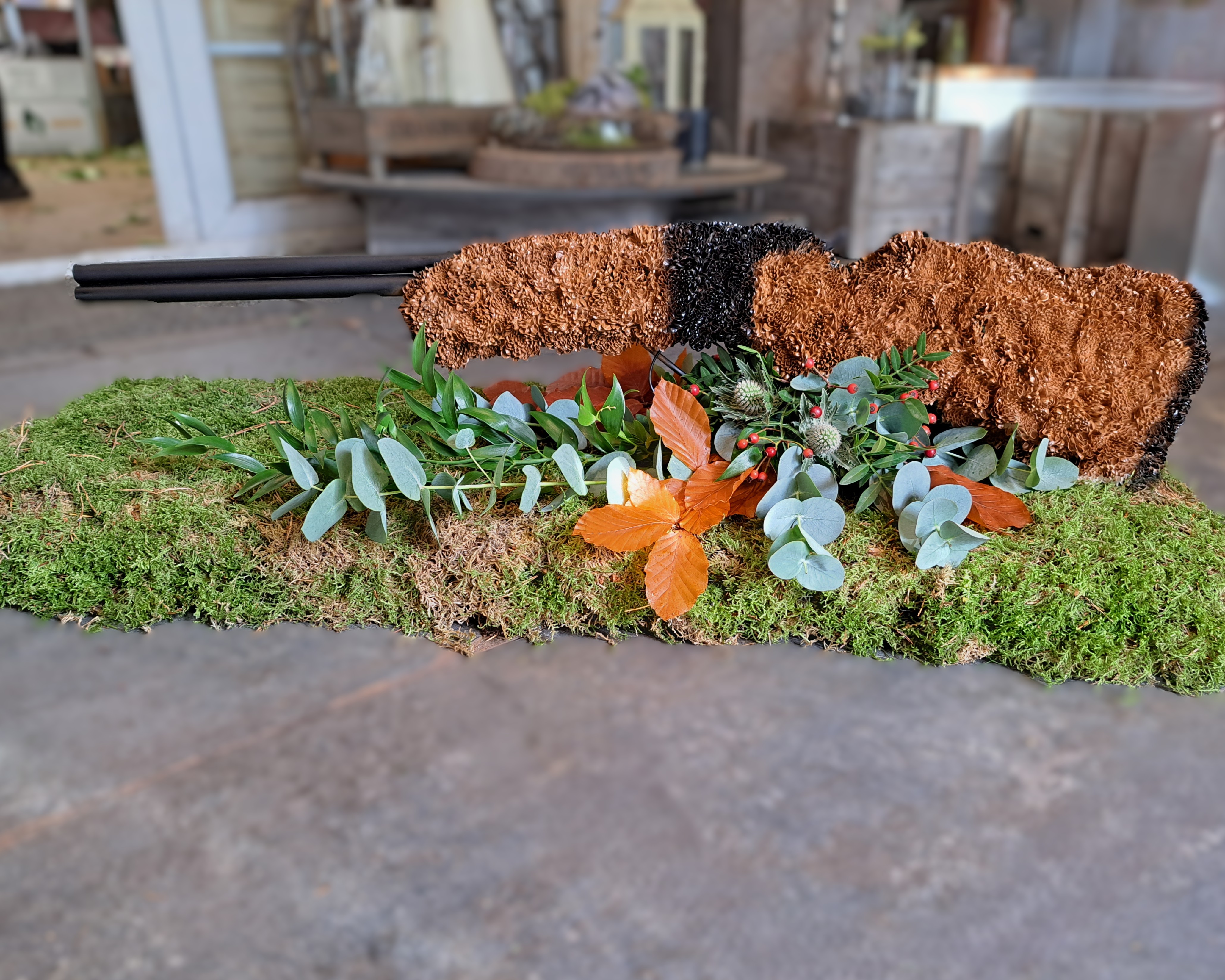 Gun-shaped funeral tribute with autumn foliage and moss