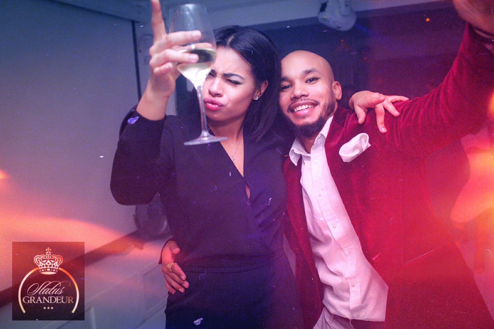 Status Grandeur event — couple celebrating with champagne, Status Grandeur logo