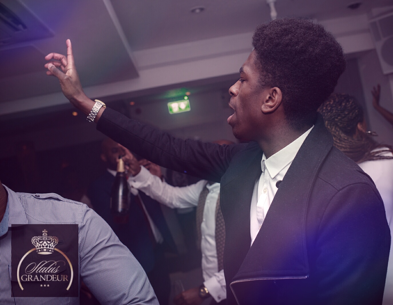 Status Grandeur event — man dancing with arm raised, Status Grandeur logo