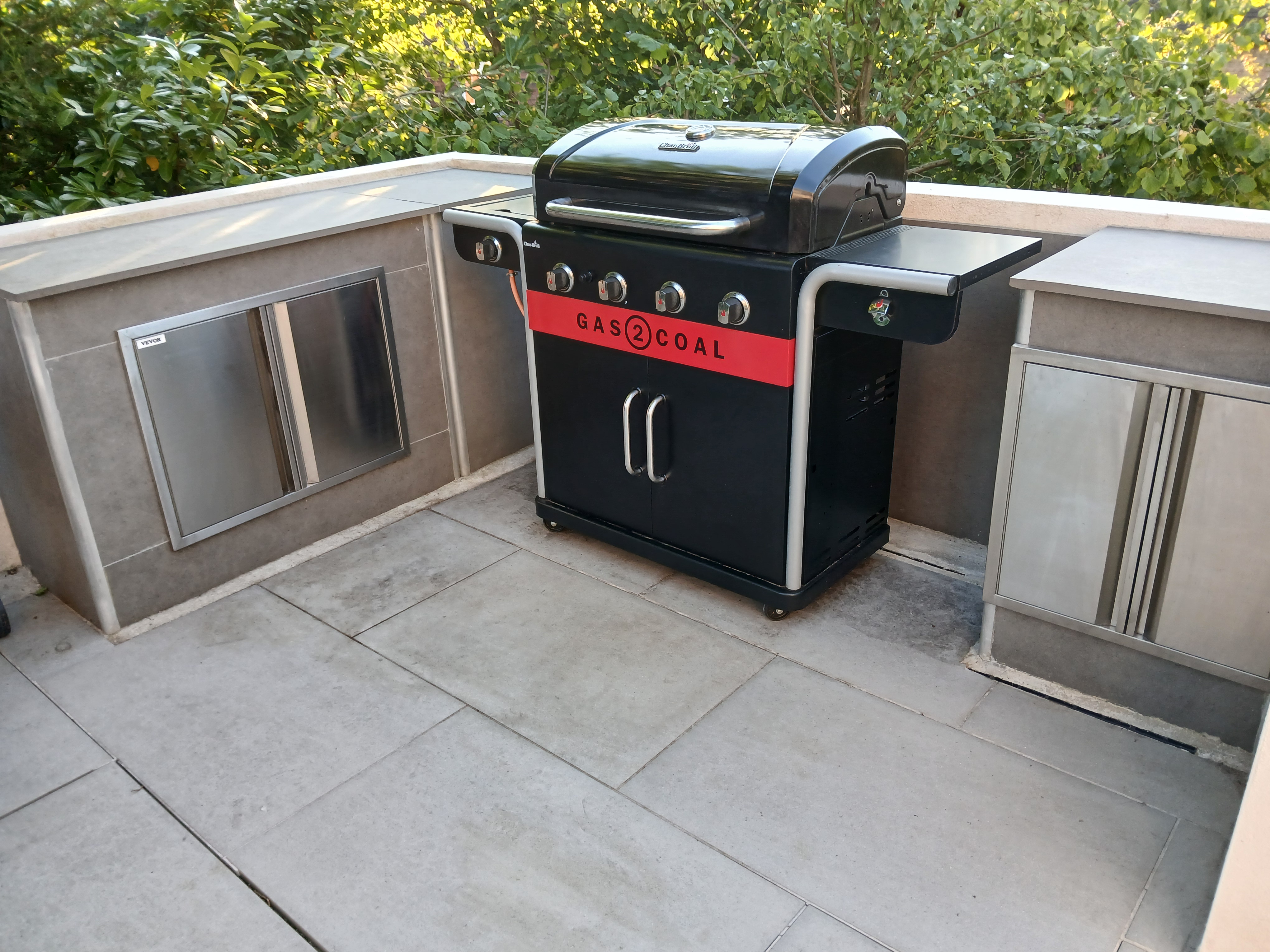 Gas2Coal grill in a VERTEO L-shaped outdoor kitchen with stainless steel doors
