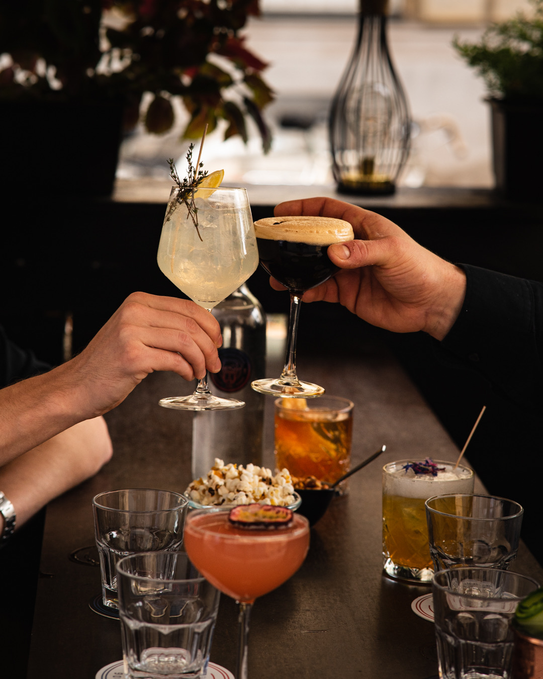 Cheers mit verschiedenen Cocktails an der Bar