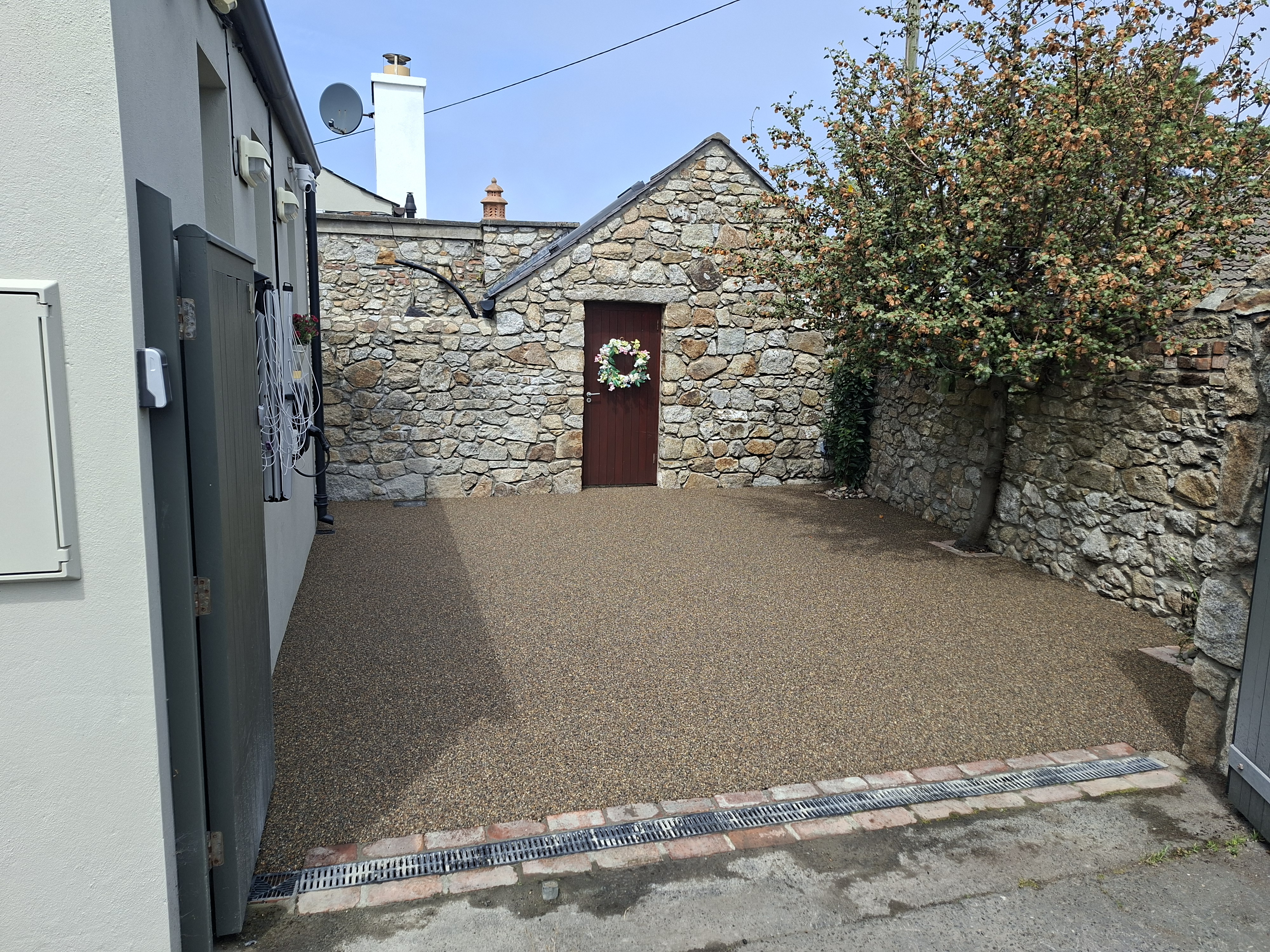 Golden brown resin bound patio area beside stone walls, clean drainage detail and neat edging