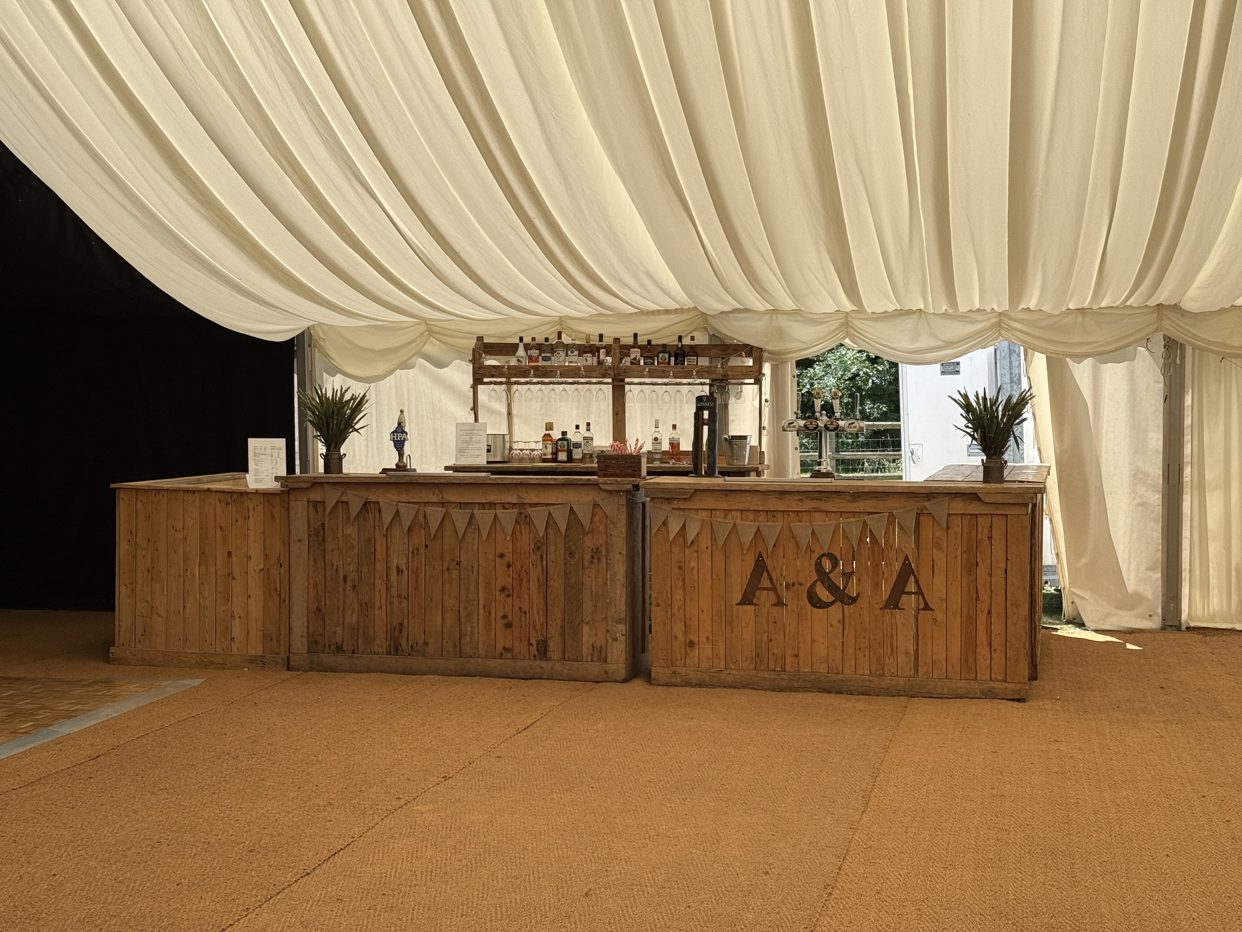 Vintage wooden bar setup with bunting inside a marquee