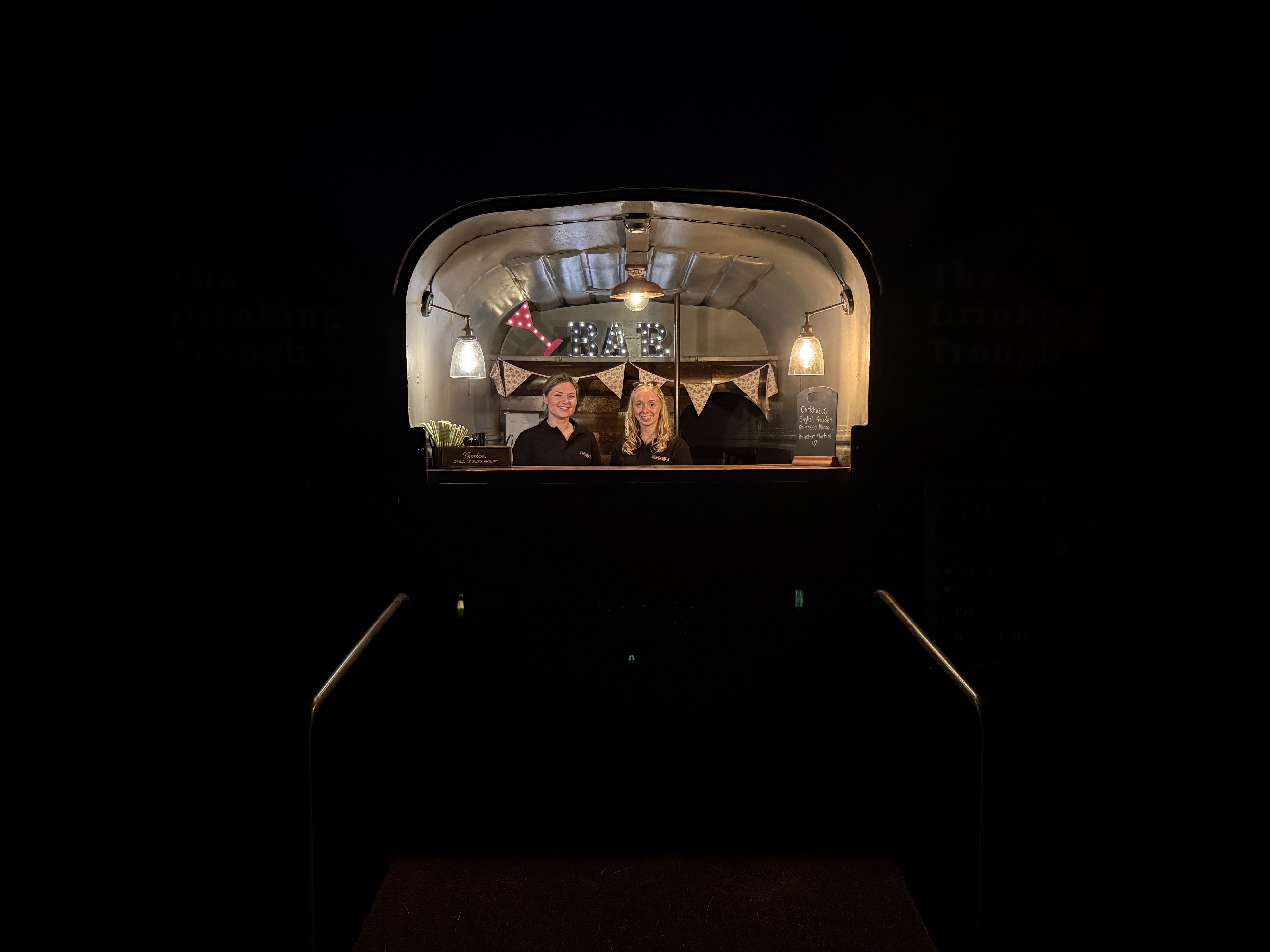 The Drinking Trough lit up at night with bar staff