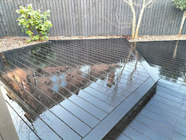 Dark grey composite decking with pebble border by Woodgate Joinery Glasgow
