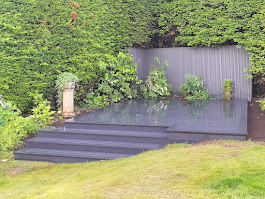 Grey composite decking with steps and hedge backdrop by Woodgate Joinery Glasgow