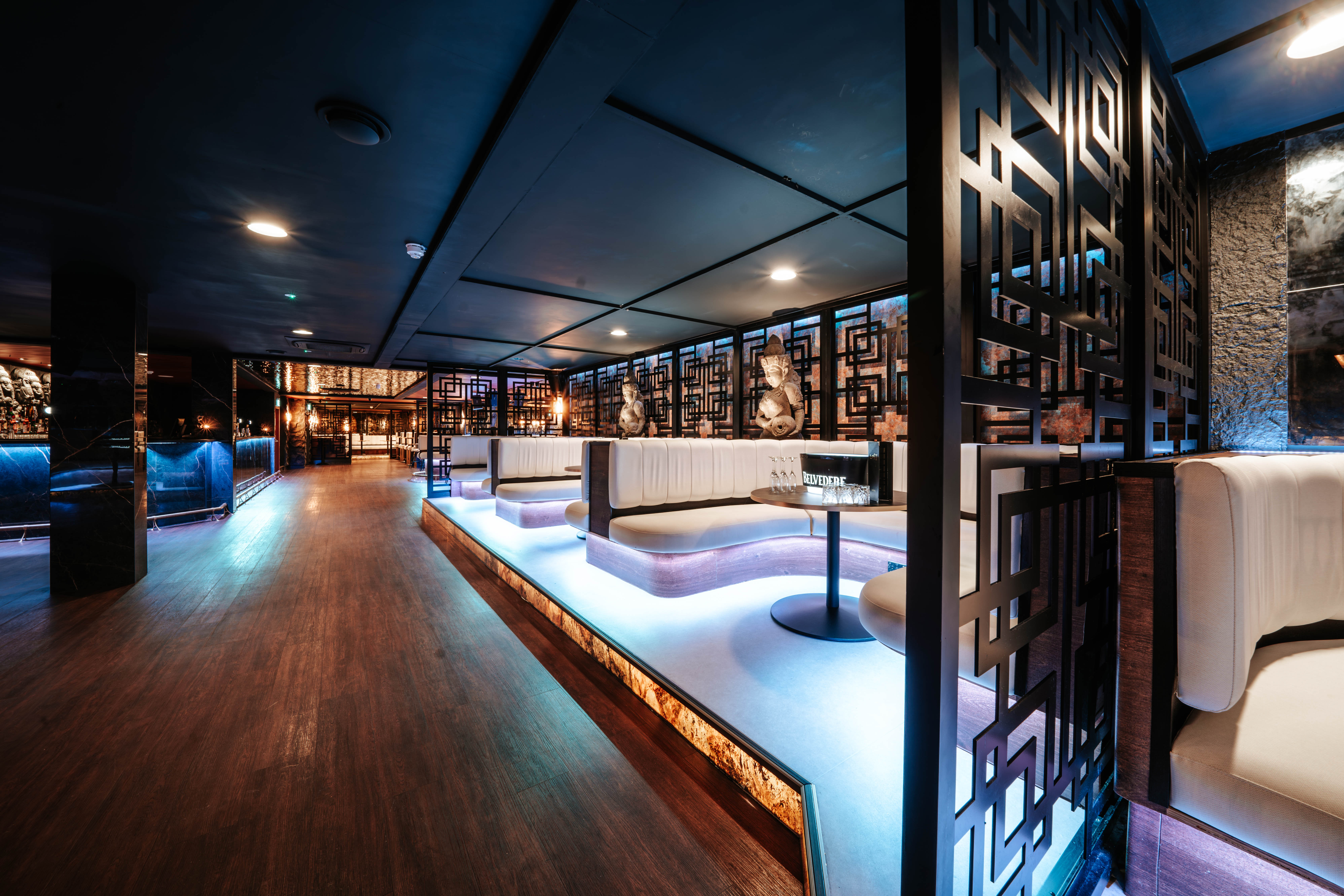 LOST Bournemouth VIP booth area with white leather seating, decorative lattice dividers, carved statues and blue-toned ambient lighting