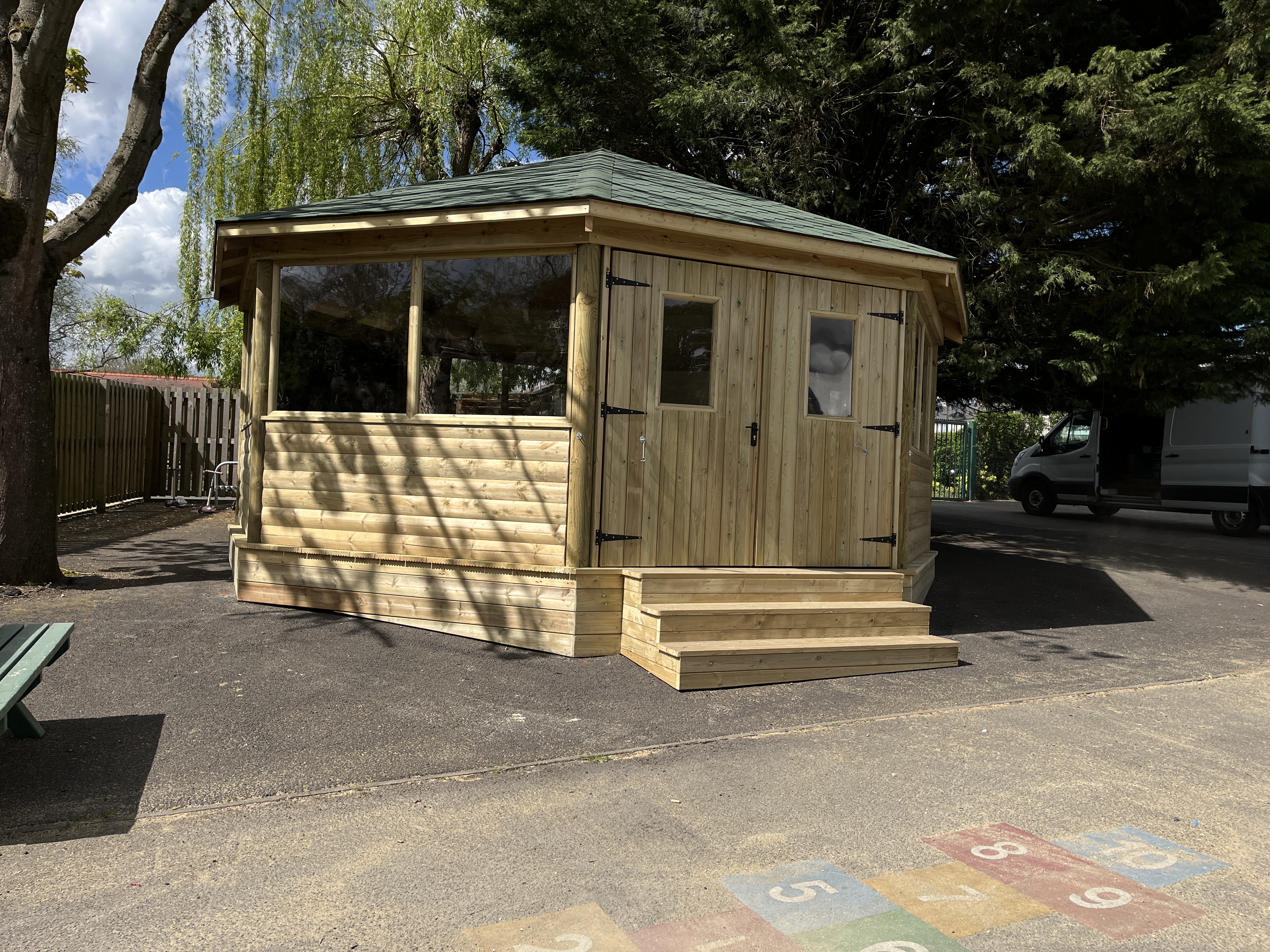 Enclosed octagonal outdoor classroom with double doors and large windows on school playground
