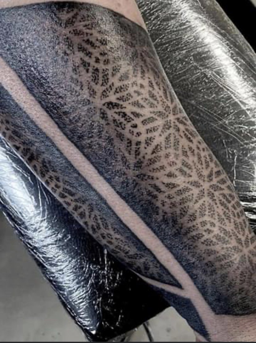 Fijn dotwork-patroon tussen zware blackwork-banden op de onderarm