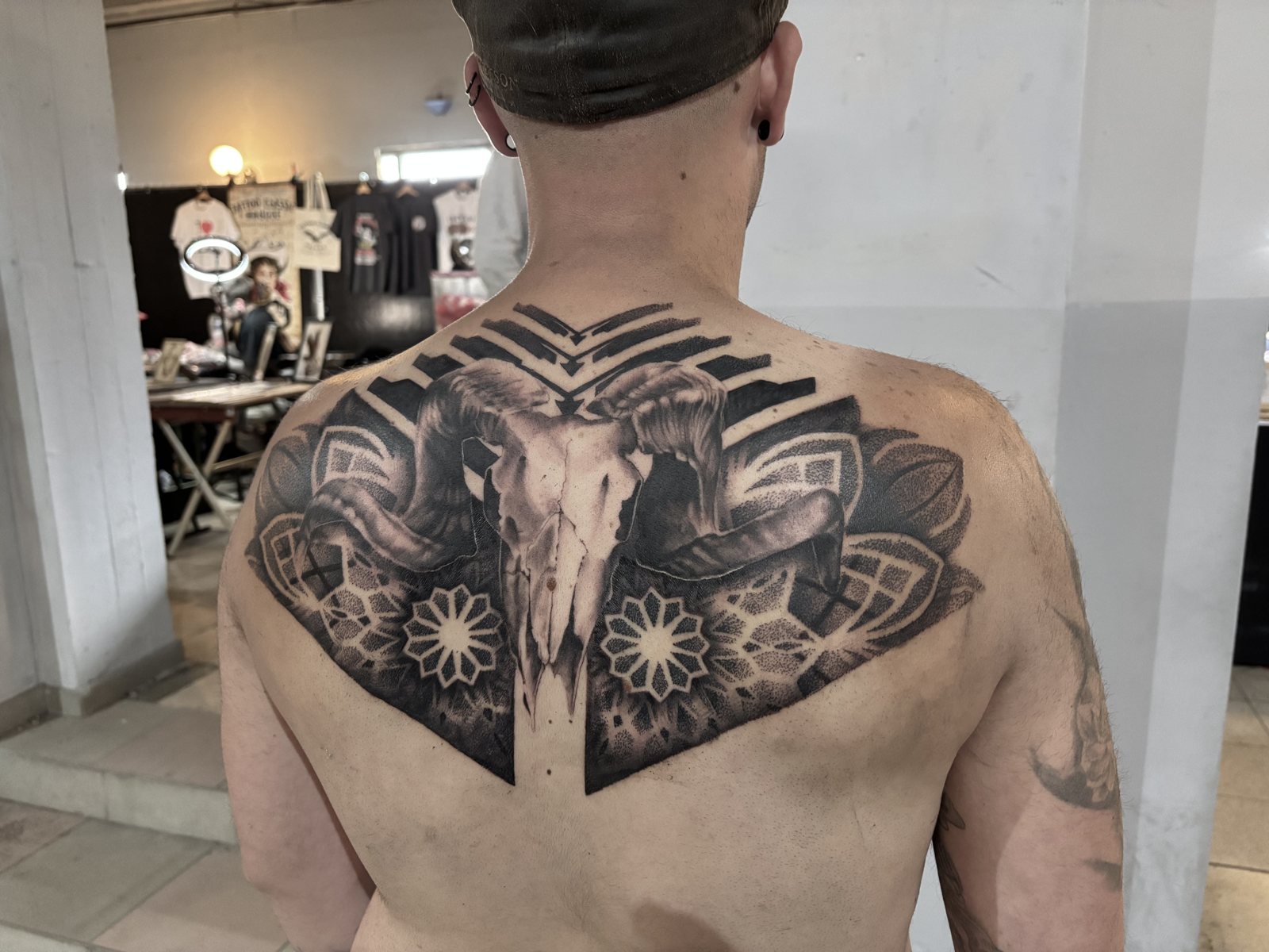 Ramschedel met mandala's, dotwork en blackwork-strepen op de bovenrug