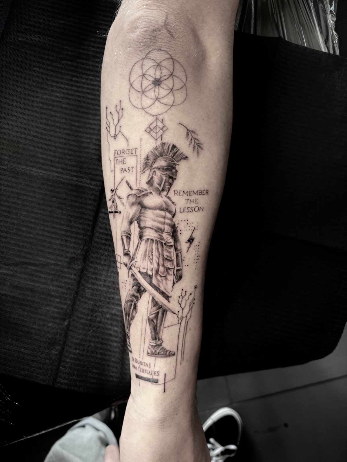 Gladiator met fijne lijnen, geometrie en tekst op de onderarm