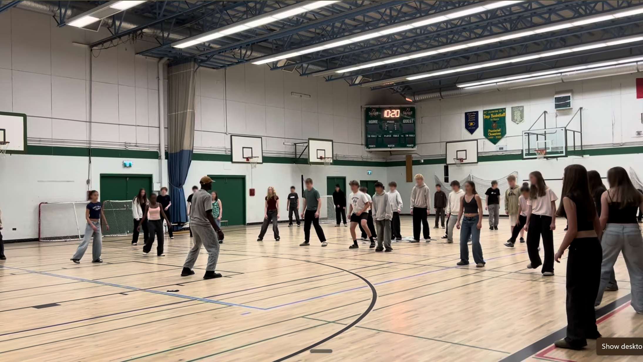 Ivan leading a groove workshop with a large group of students in a school gymnasium
