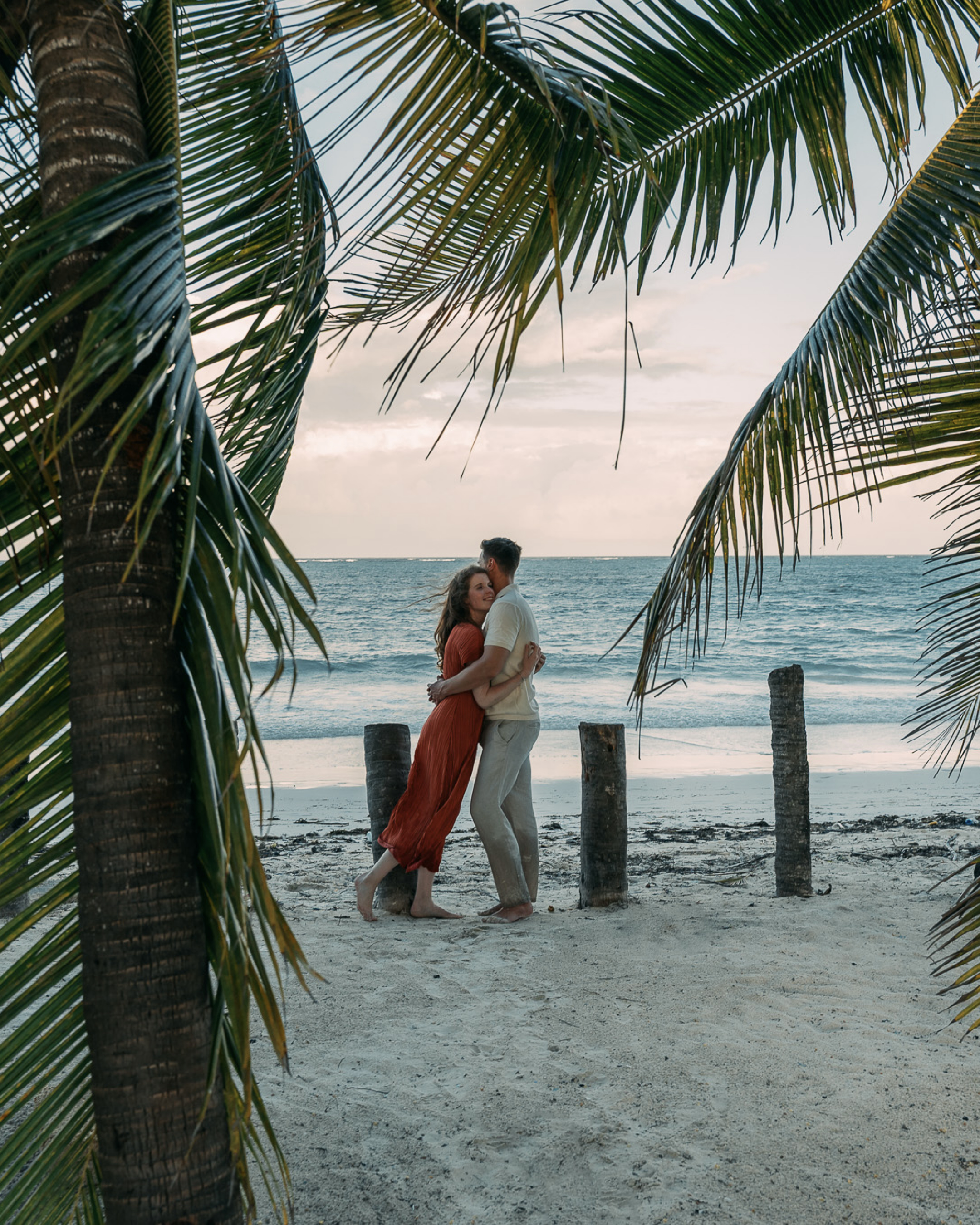 Romantic couple under palm trees at sunset Zanzibar beach