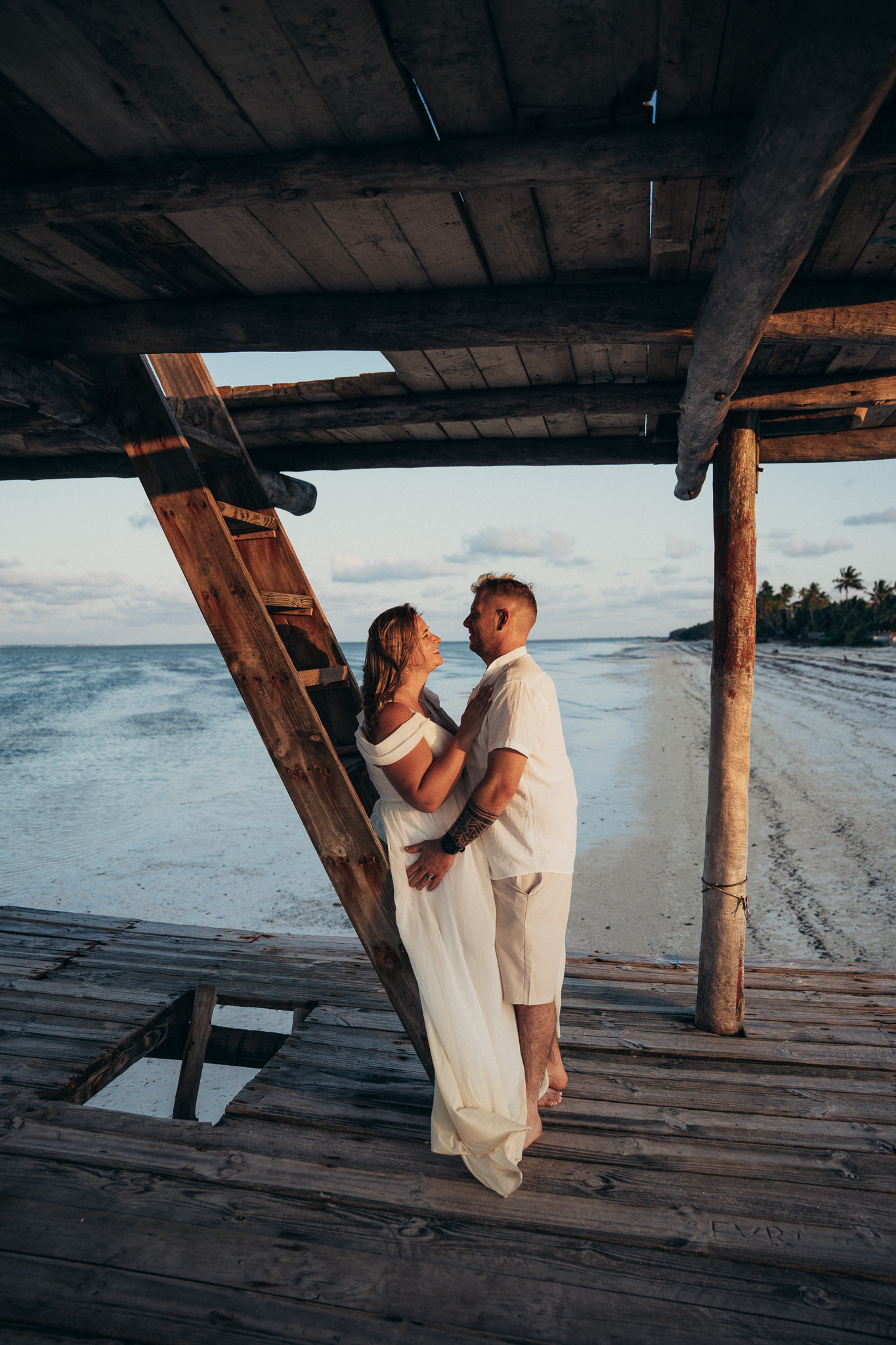 Couple embracing on wooden pier at golden hour Zanzibar