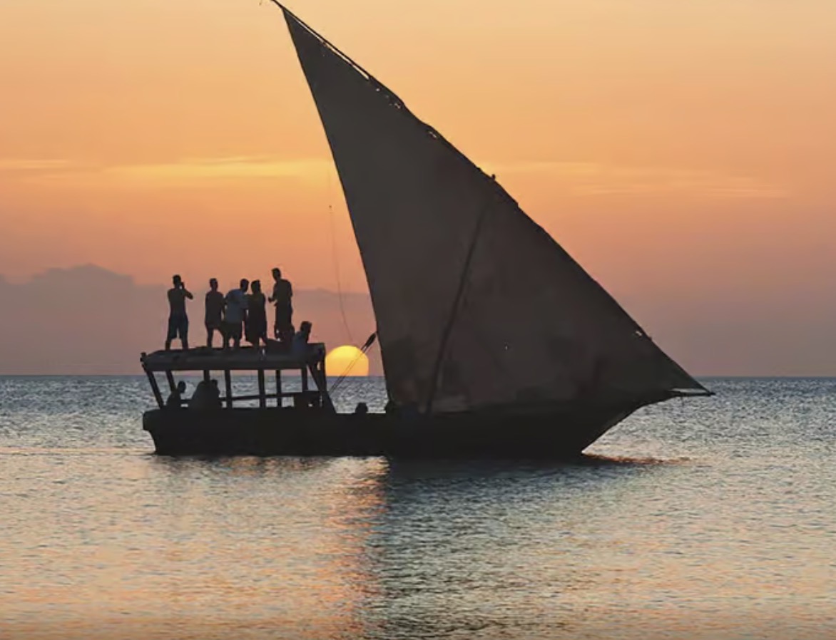 Traditional dhow sailboat silhouette against golden sunset on the Indian Ocean in Zanzibar