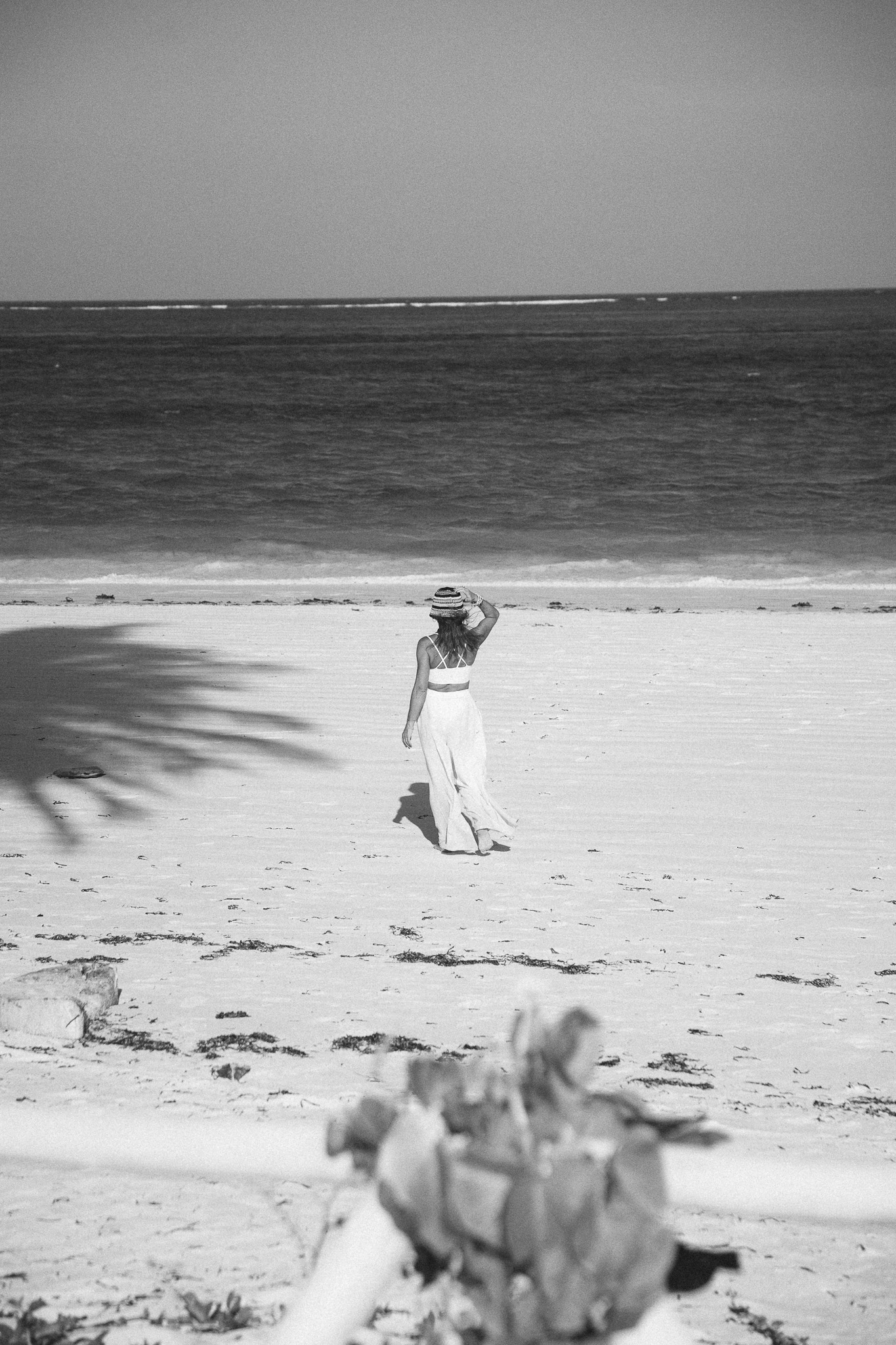 Woman in white dress walking on Zanzibar beach - black and white