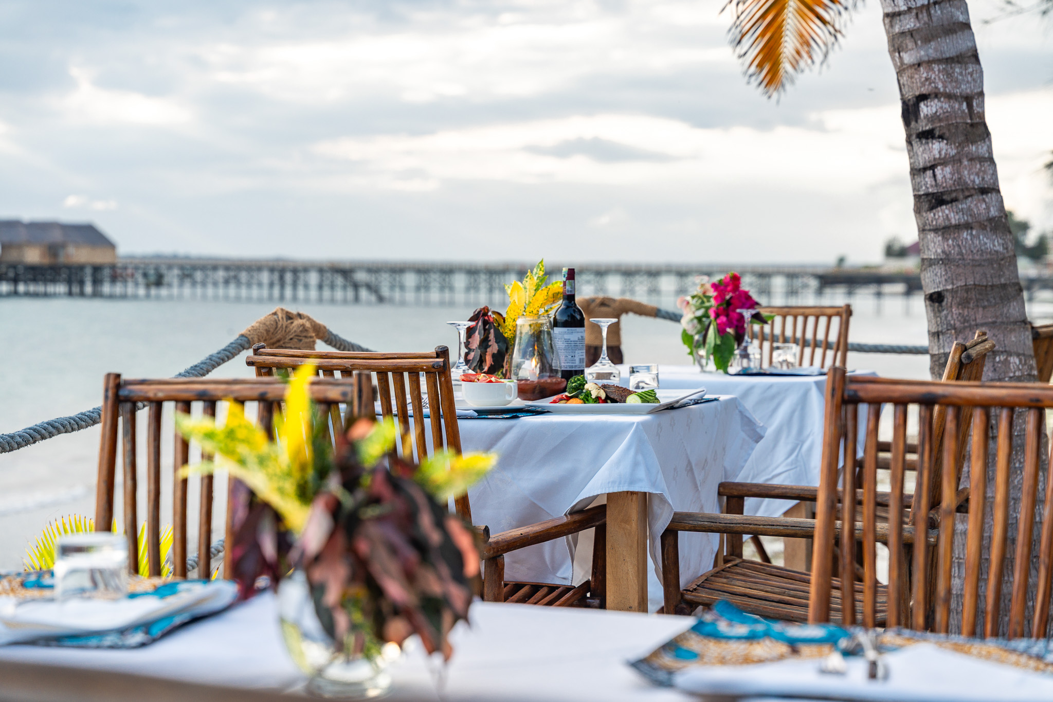 Restaurant tables set with white linen, flowers and ocean view at Tunu Beach Zanzibar
