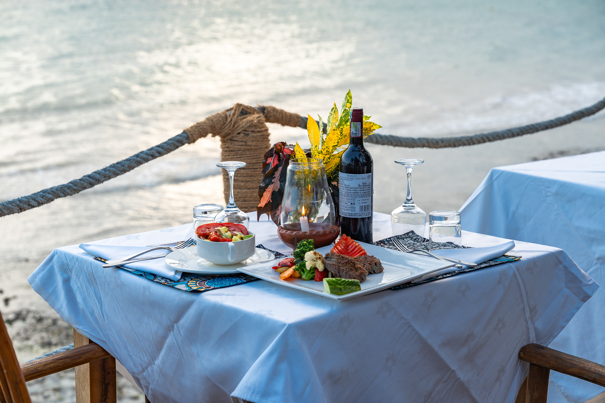 Romantic dinner table for two with wine, candle and fresh food overlooking the Indian Ocean