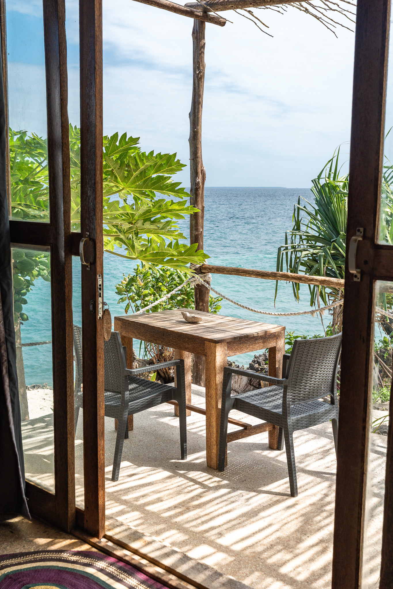 Private ocean-view terrace with wooden table and chairs at Tunu Beach Zanzibar