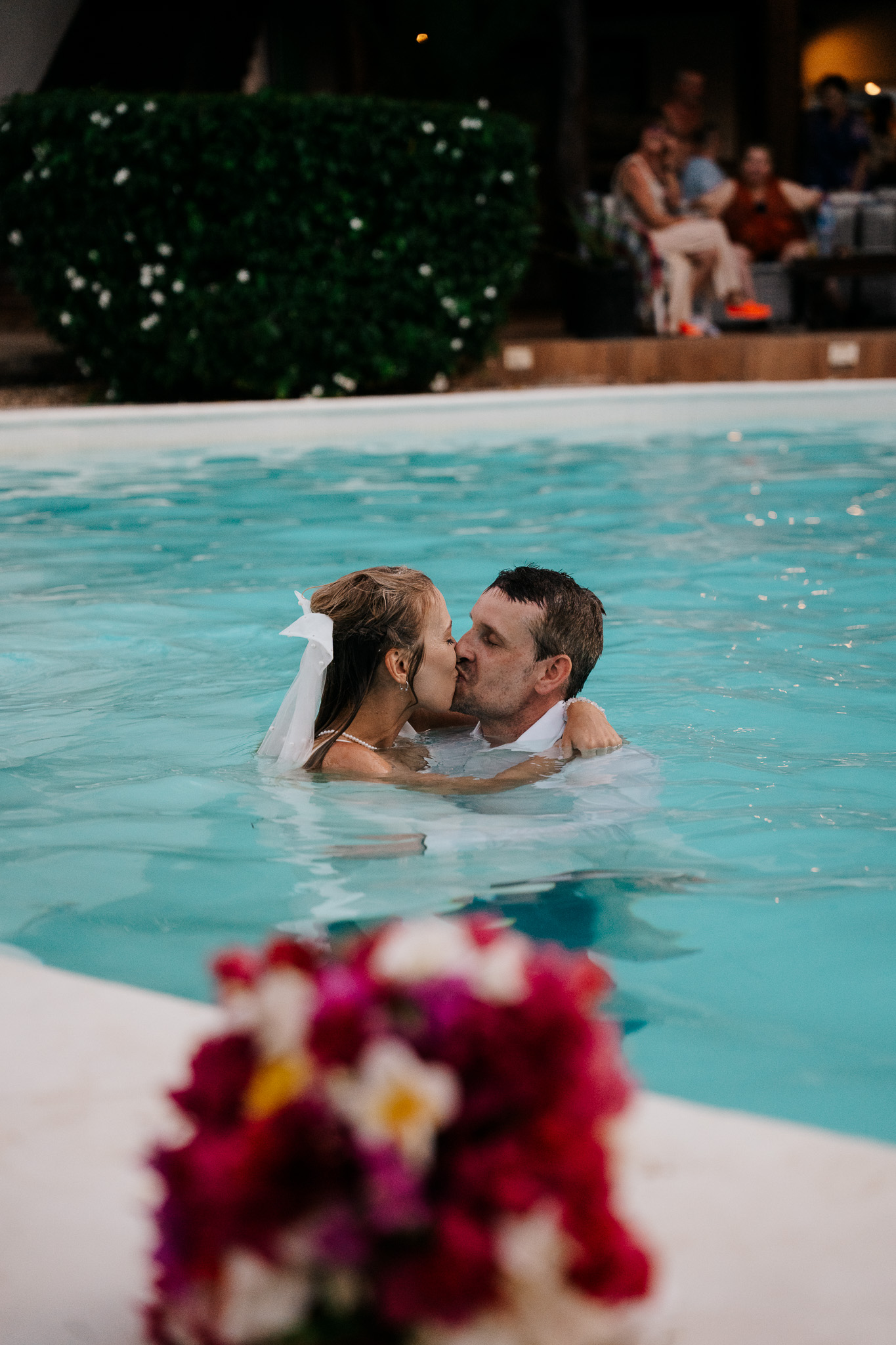 Couple kissing in pool with bouquet