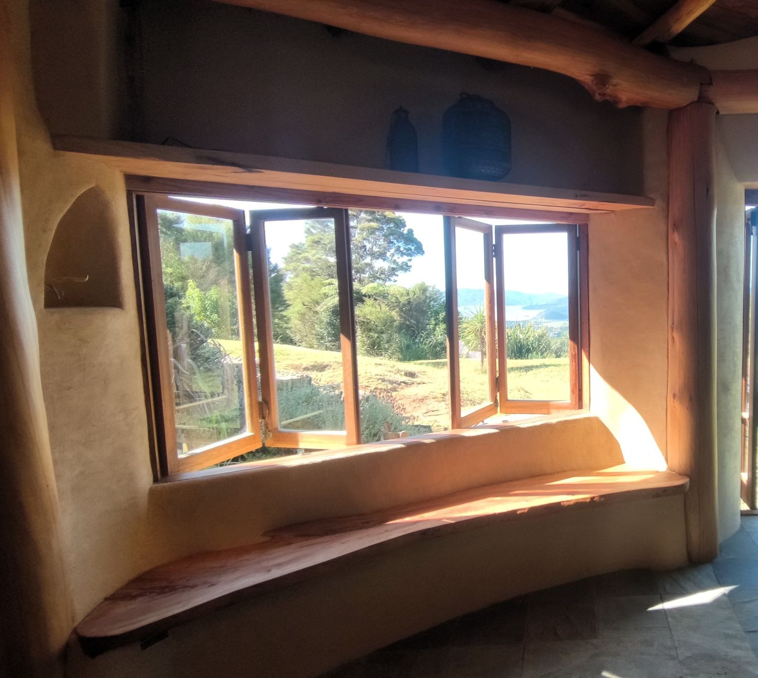 Großes Holzfenster in einem Lehmhaus – passives Solardesign für natürliche Wärme