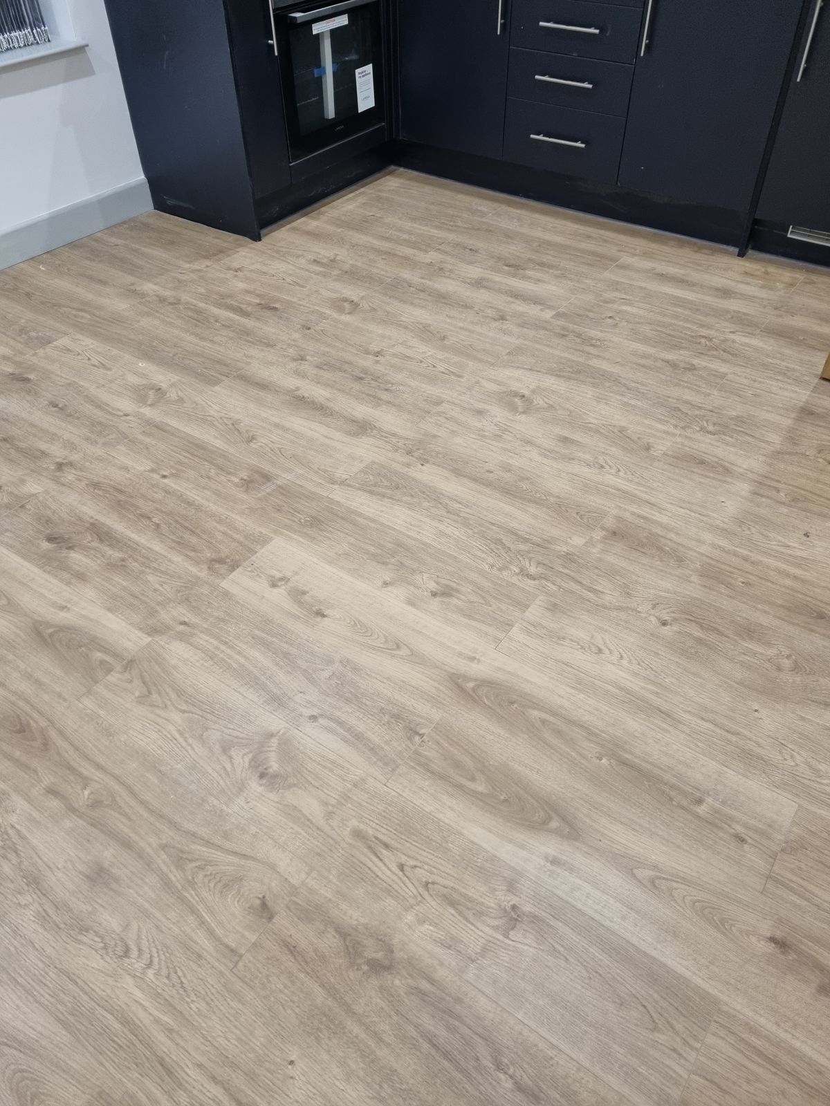 Kitchen with light brown laminate wood flooring and black cabinets