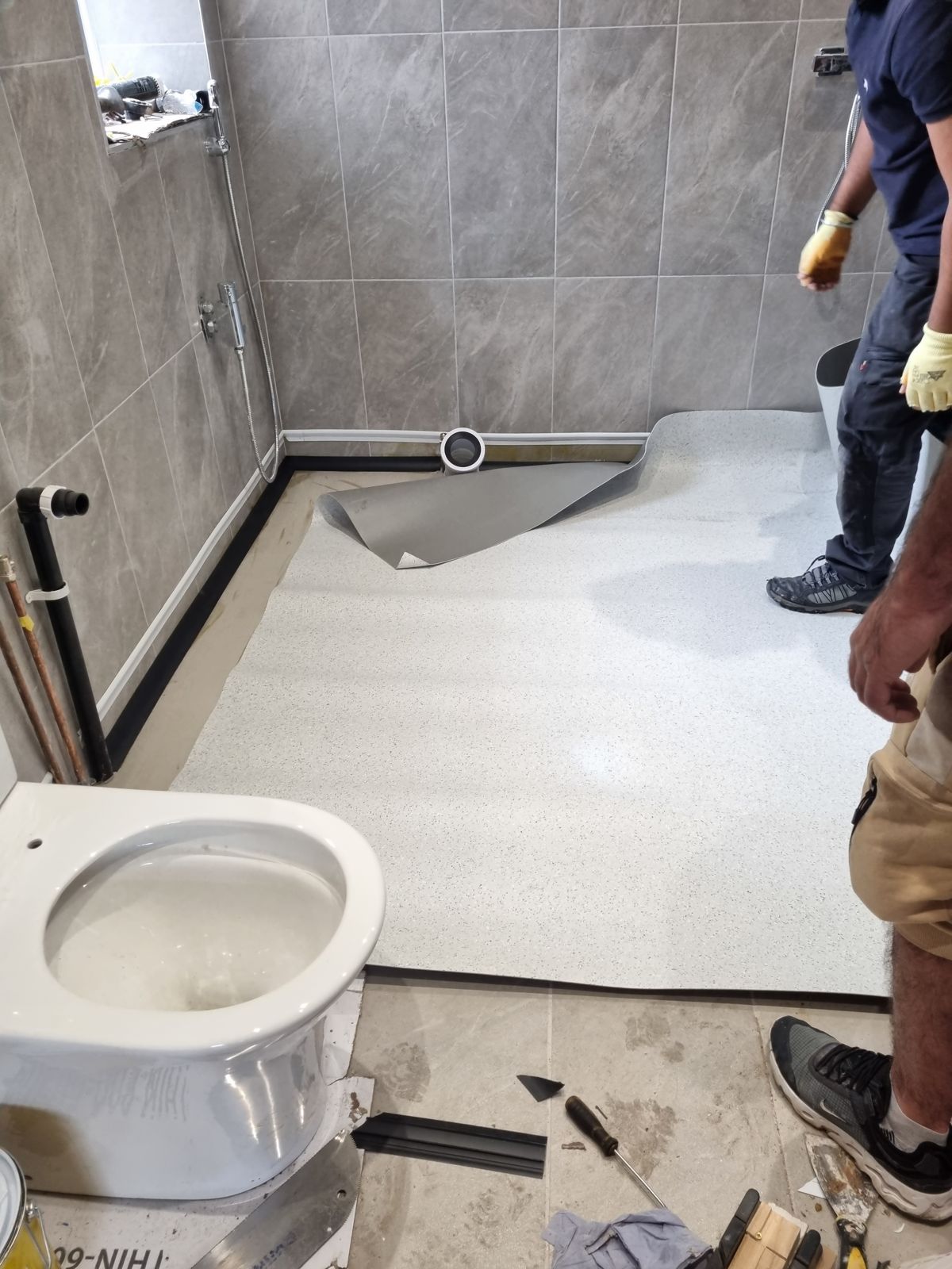 Team fitting vinyl in bathroom