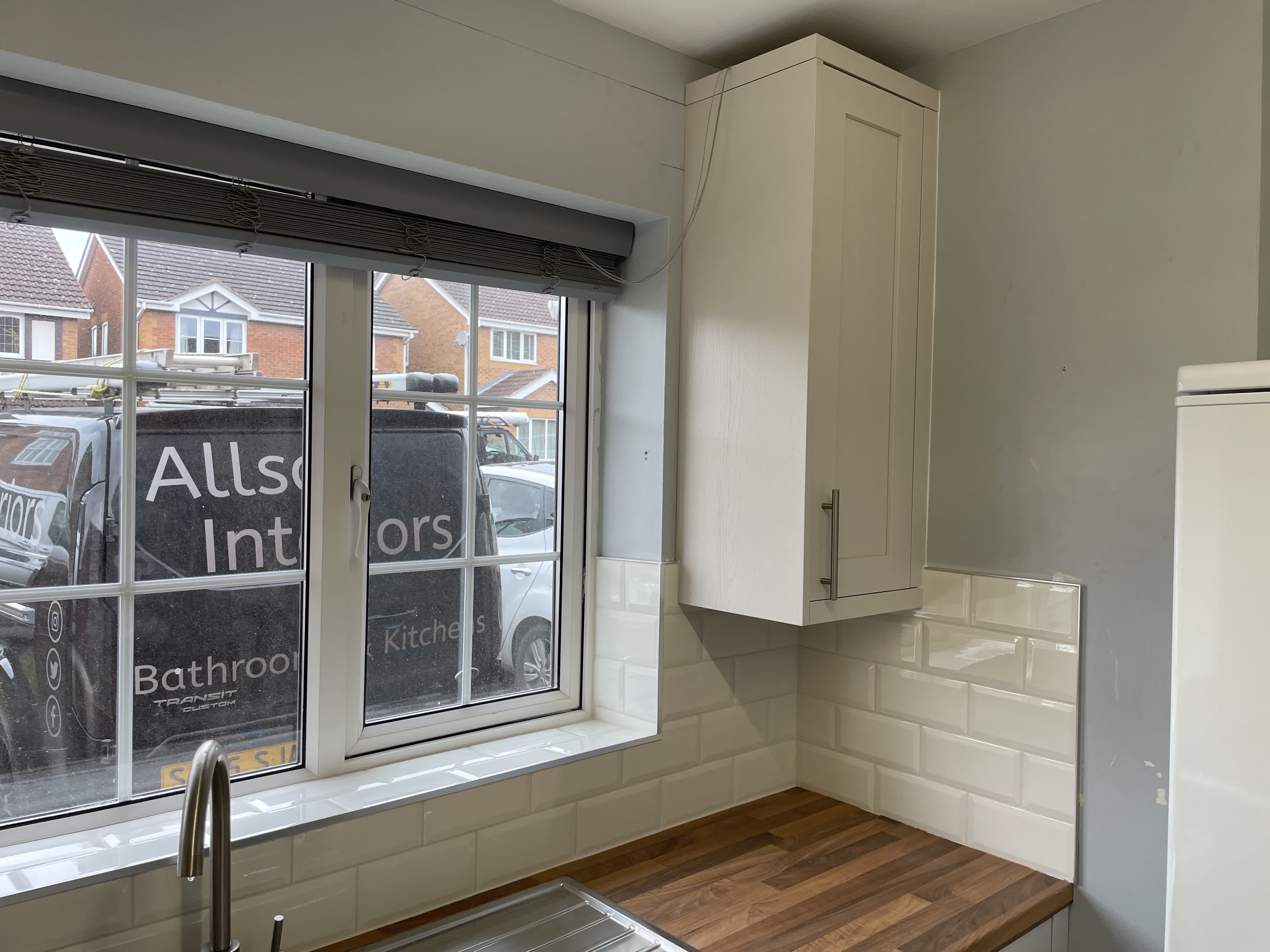 Kitchen sink area with wooden worktop and subway tile splashback