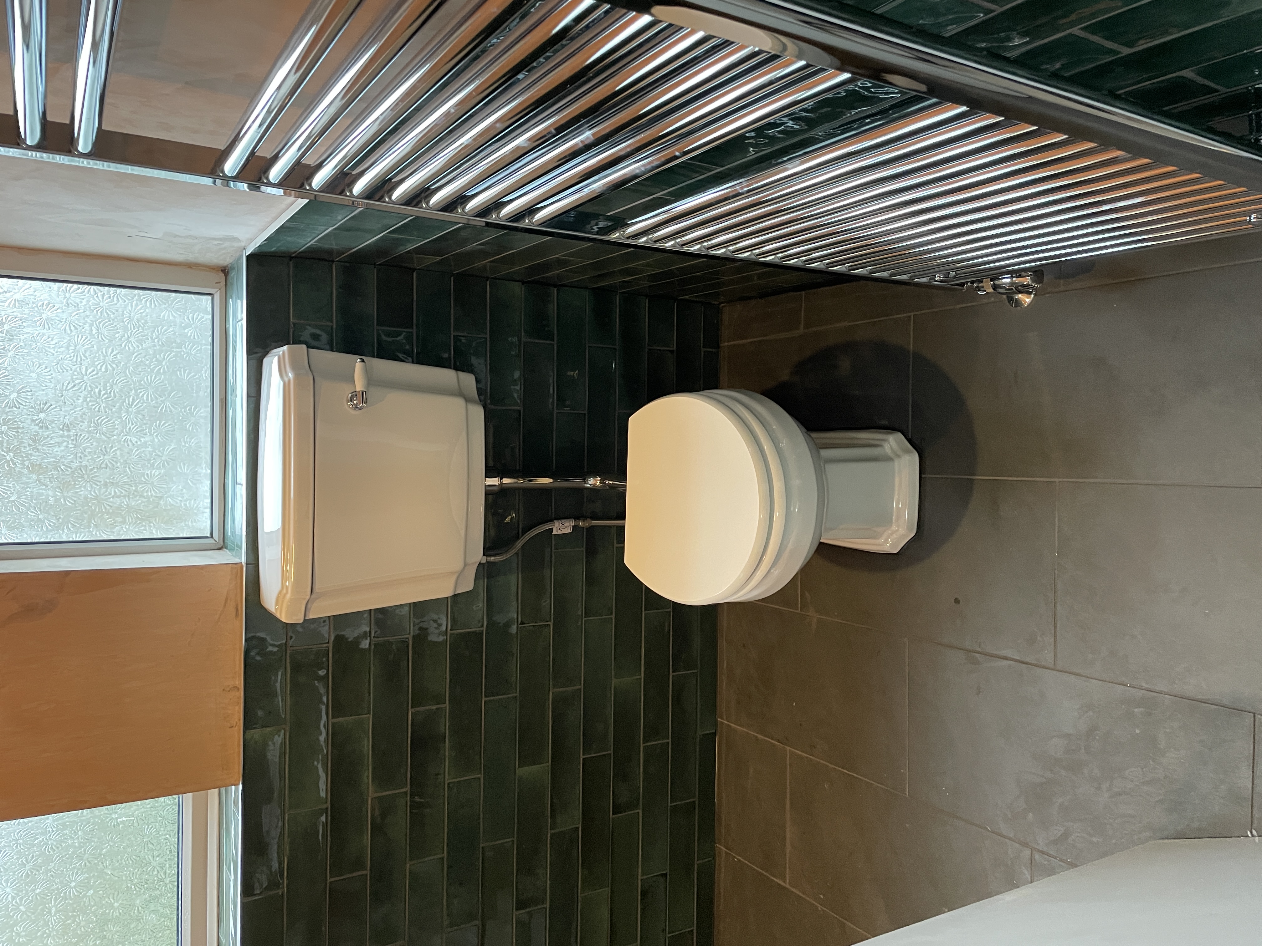 Traditional bathroom with green tiles, frosted windows and towel warmer