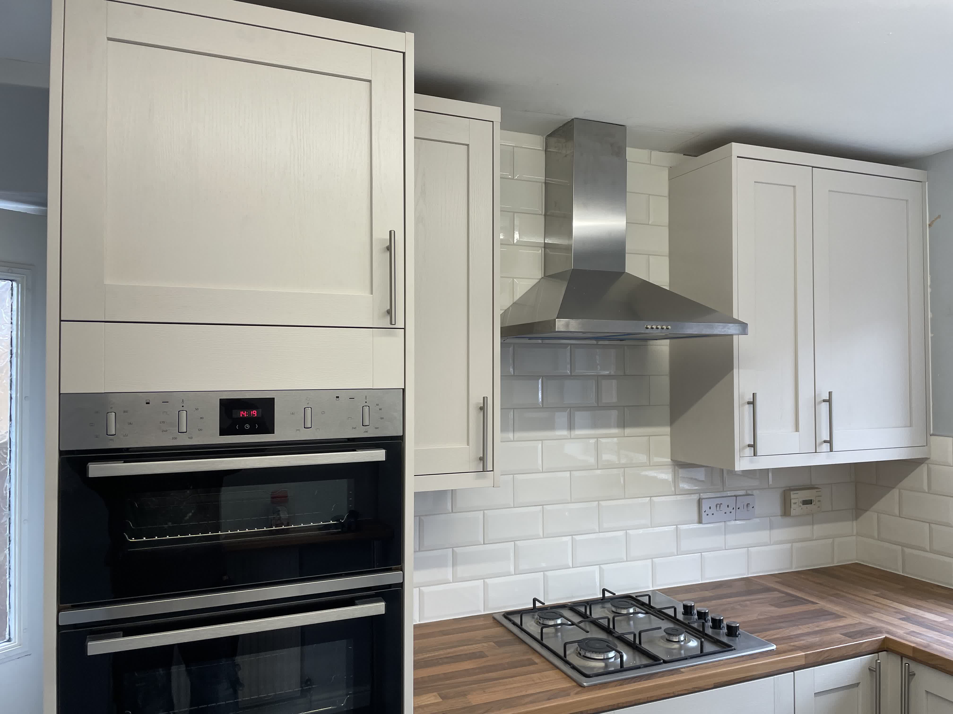 Kitchen with cream shaker cabinets, wooden worktops and double oven