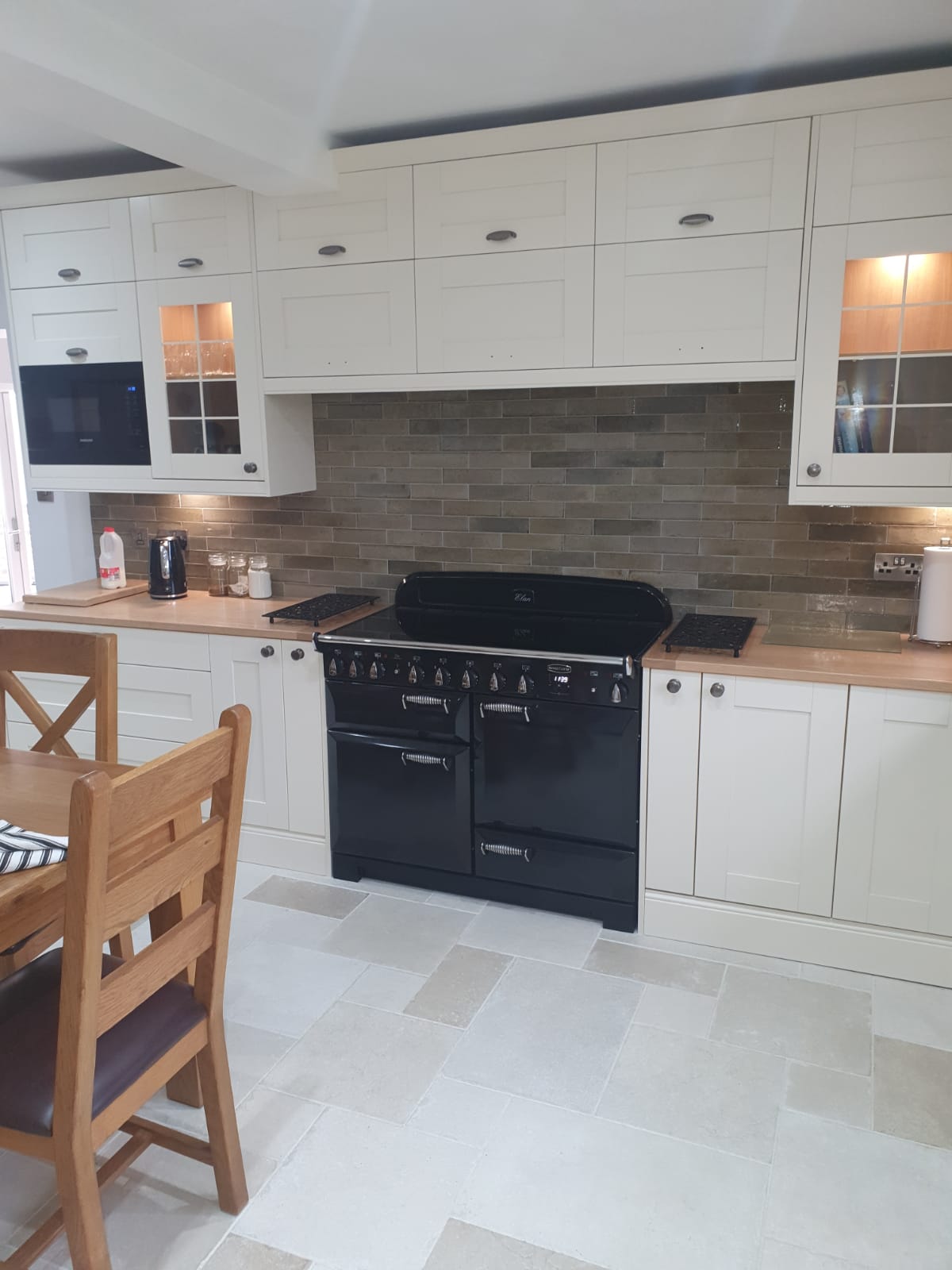Traditional kitchen with cream shaker cabinets, black range cooker and glass-fronted cabinets