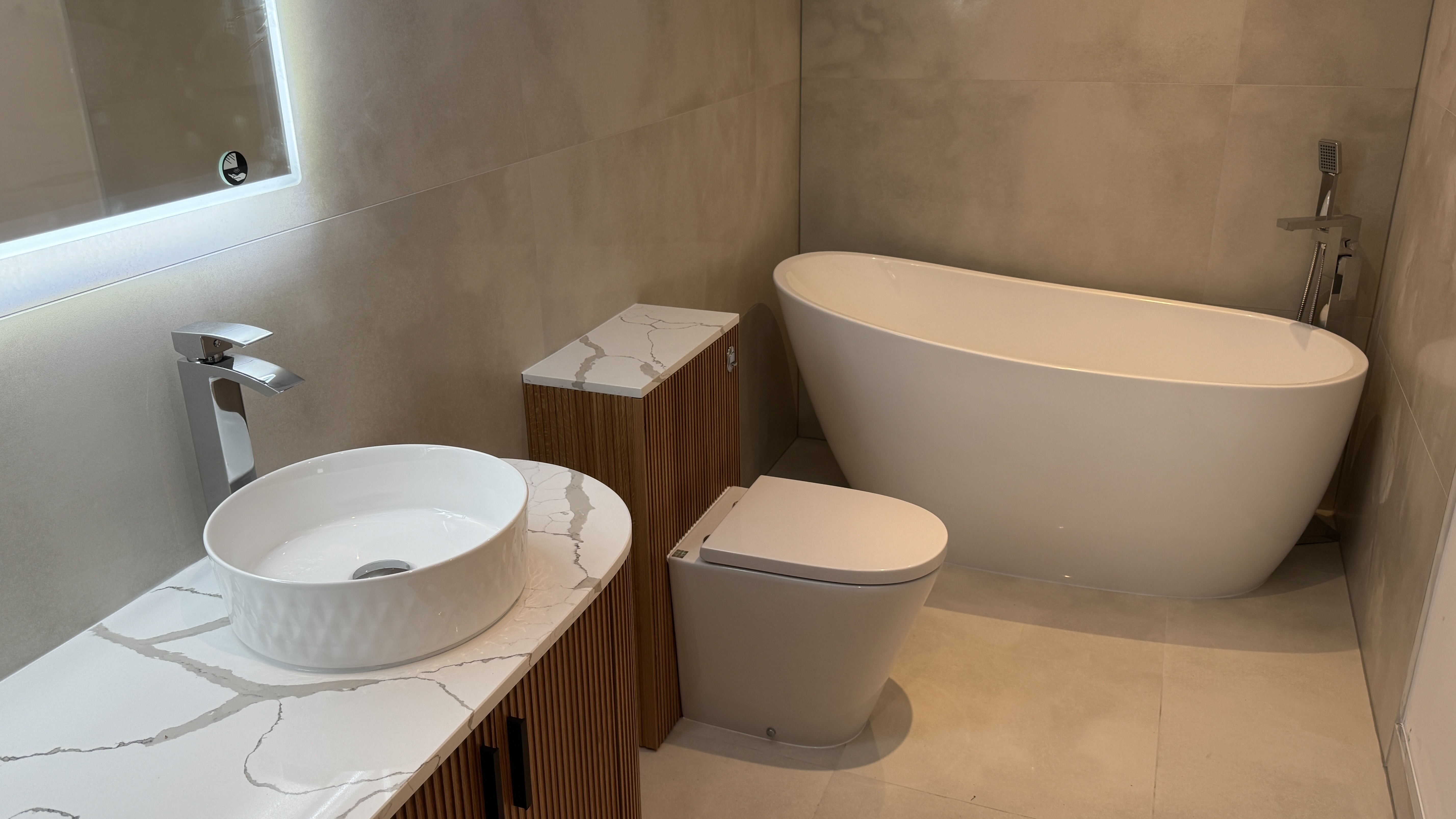 Modern bathroom with freestanding bath, backlit mirror and vessel sink