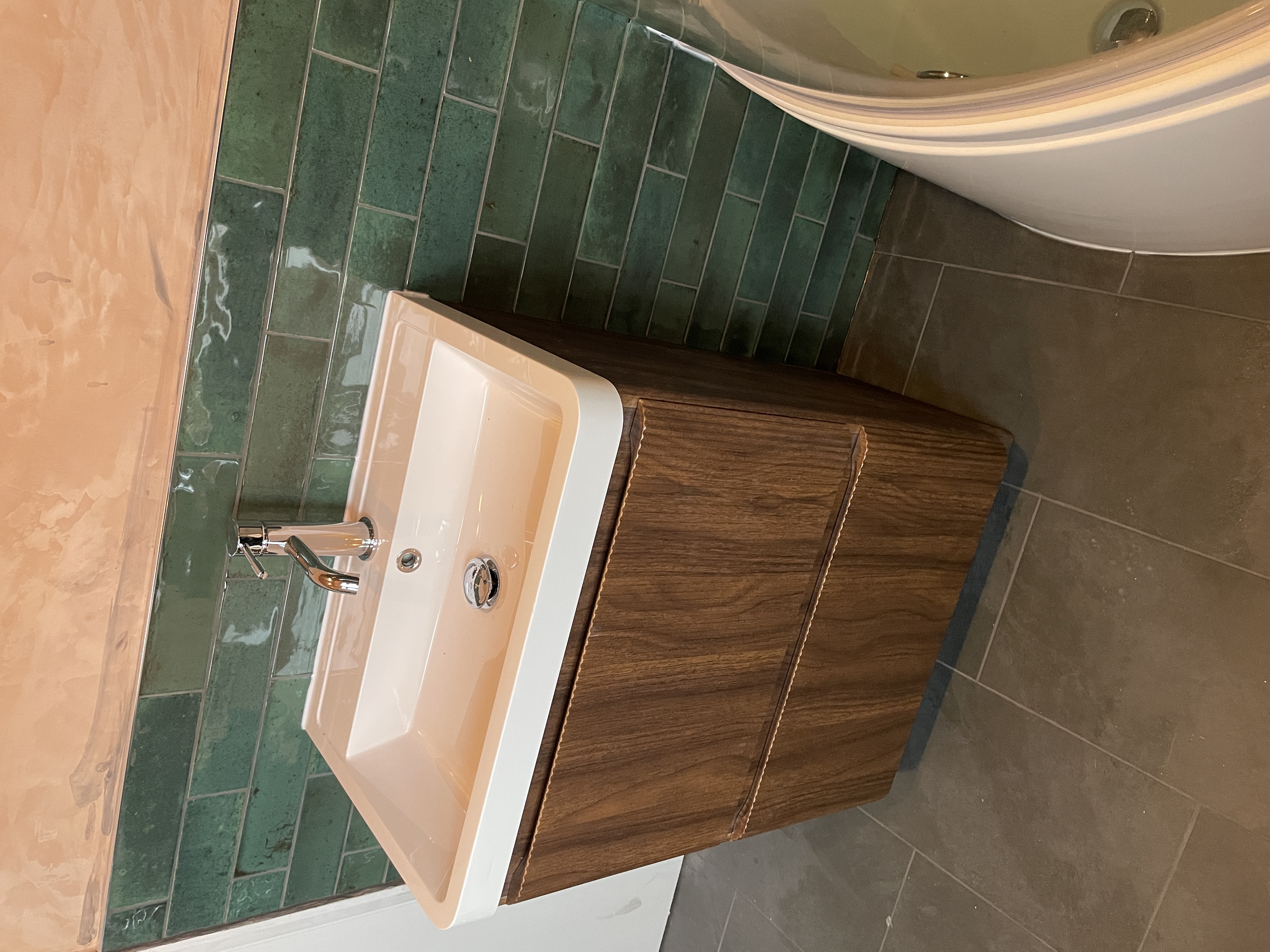 Bathroom vanity with green subway tiles and terracotta walls