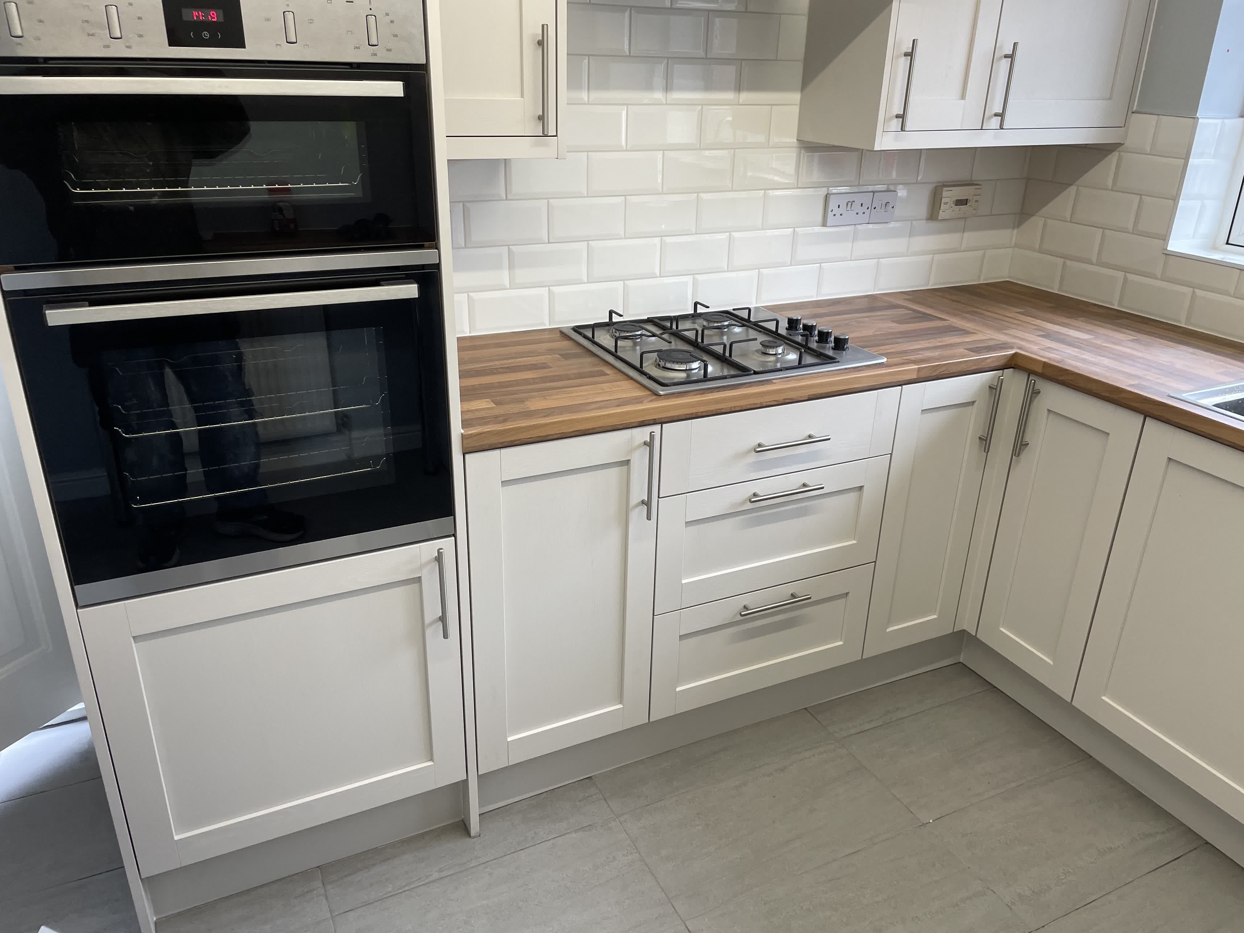 Kitchen with white shaker cabinets, wooden countertops and gas hob