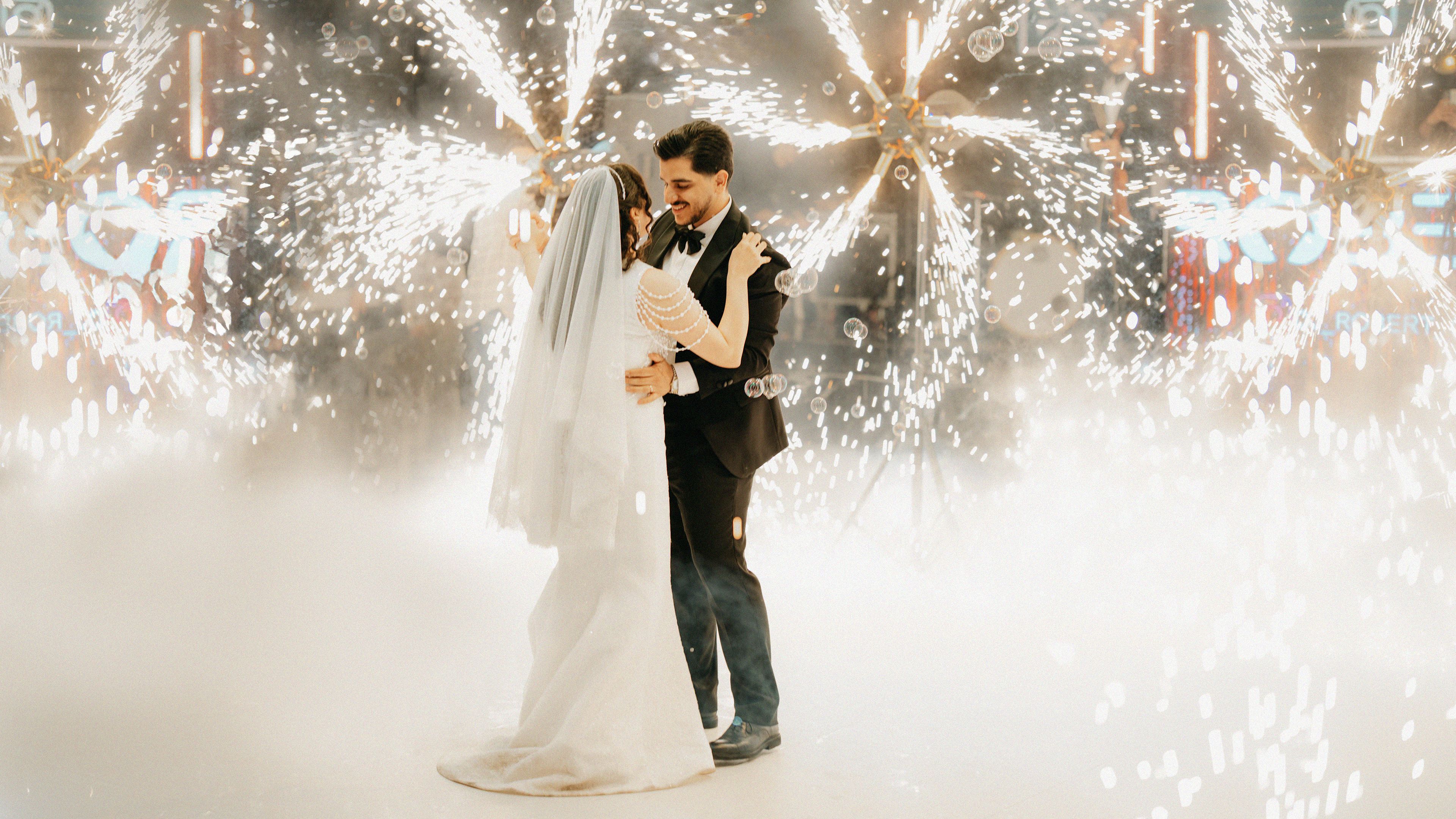 Wedding couple sharing their first dance surrounded by sparklers and fog